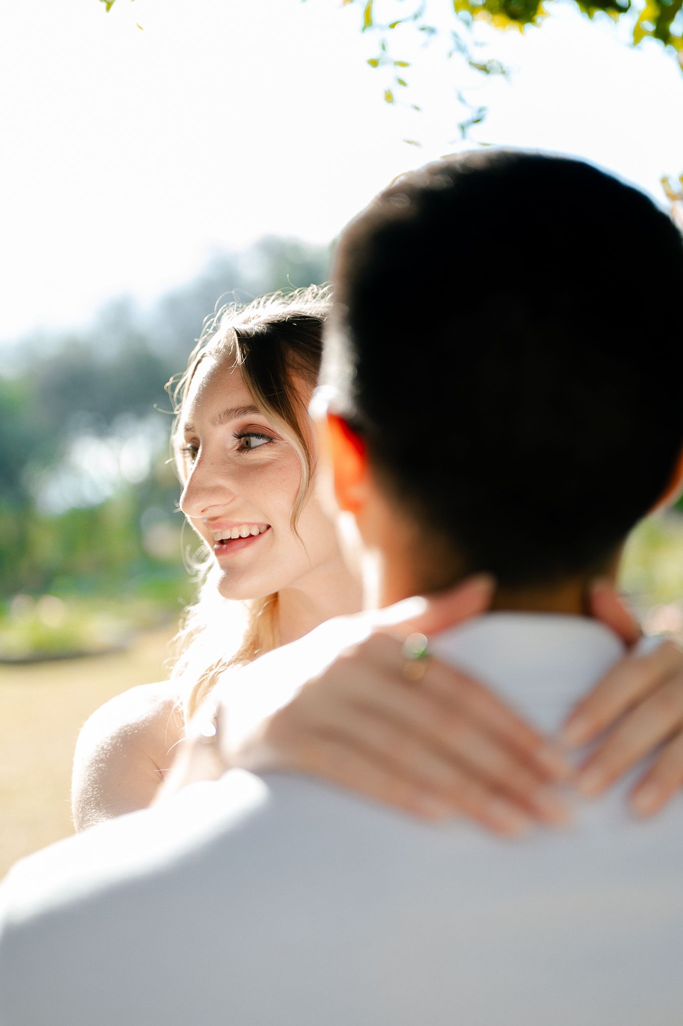 A tender moment captured between a couple in sunlit outdoor setting with warm natural lighting.