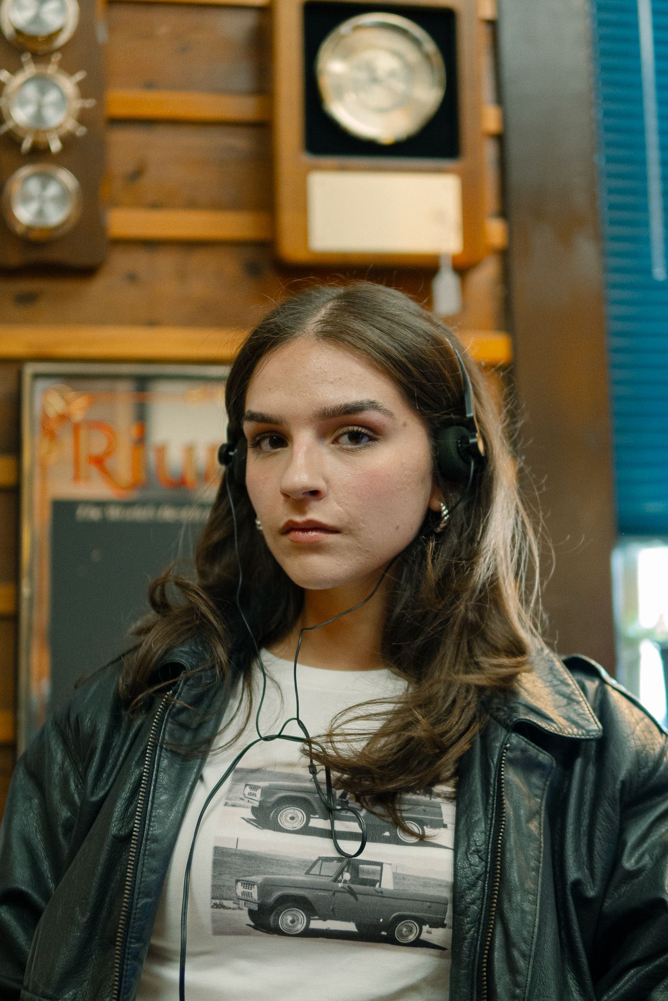 A person wearing a black leather jacket and white graphic t-shirt gazes off-camera in a series of connected portraits.