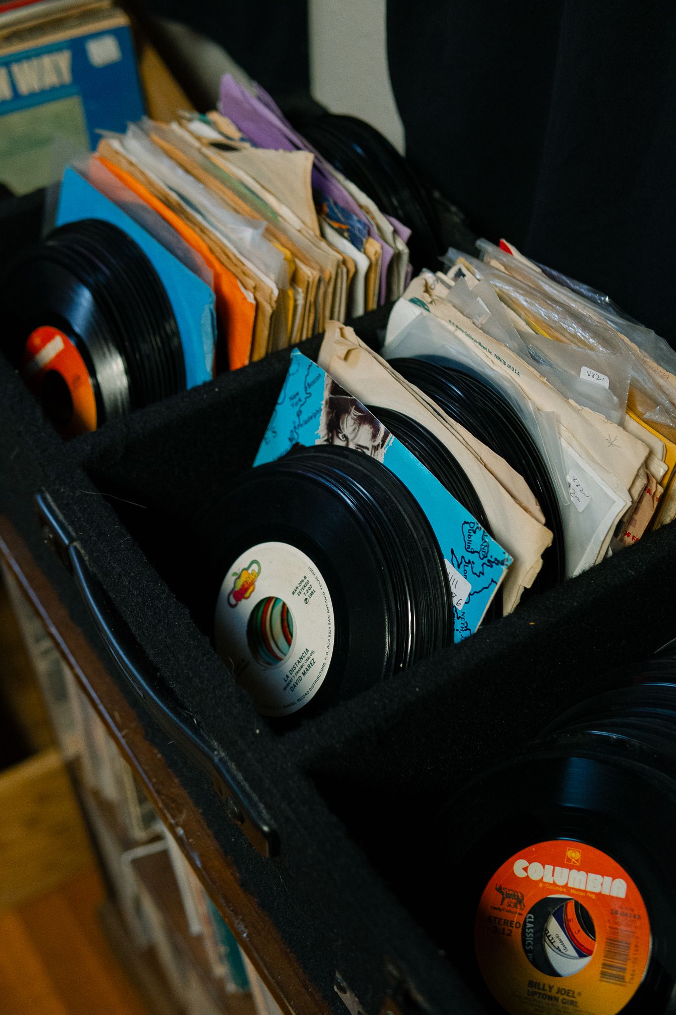 A collection of vintage vinyl records stacked together showing their edges and labels in moody lighting.