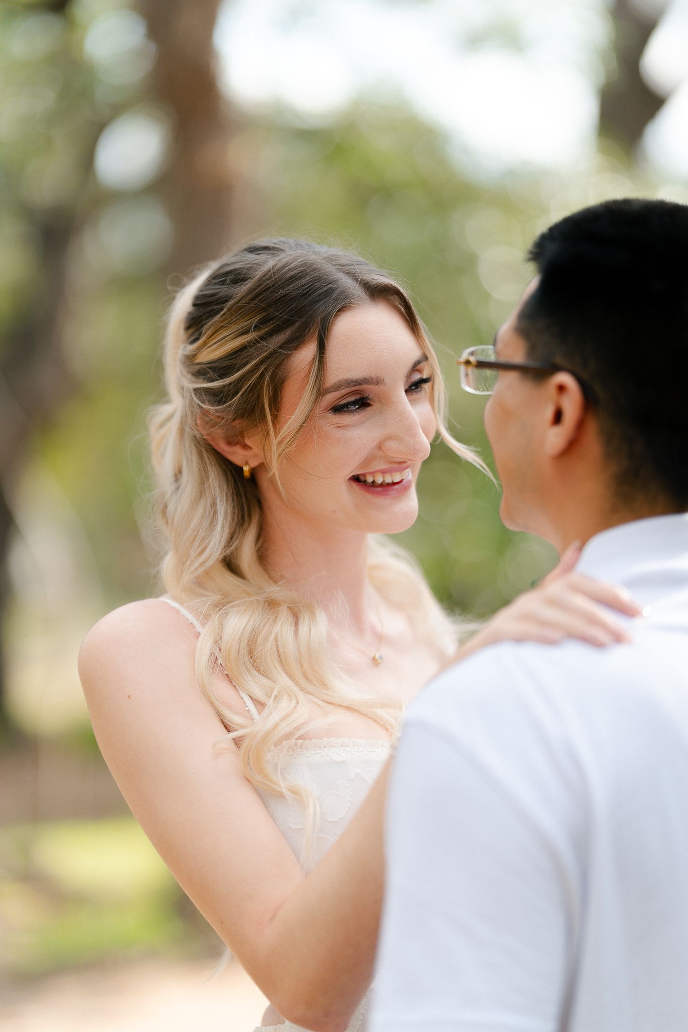 A romantic couple shares a tender moment outdoors with soft natural lighting and blurred background.