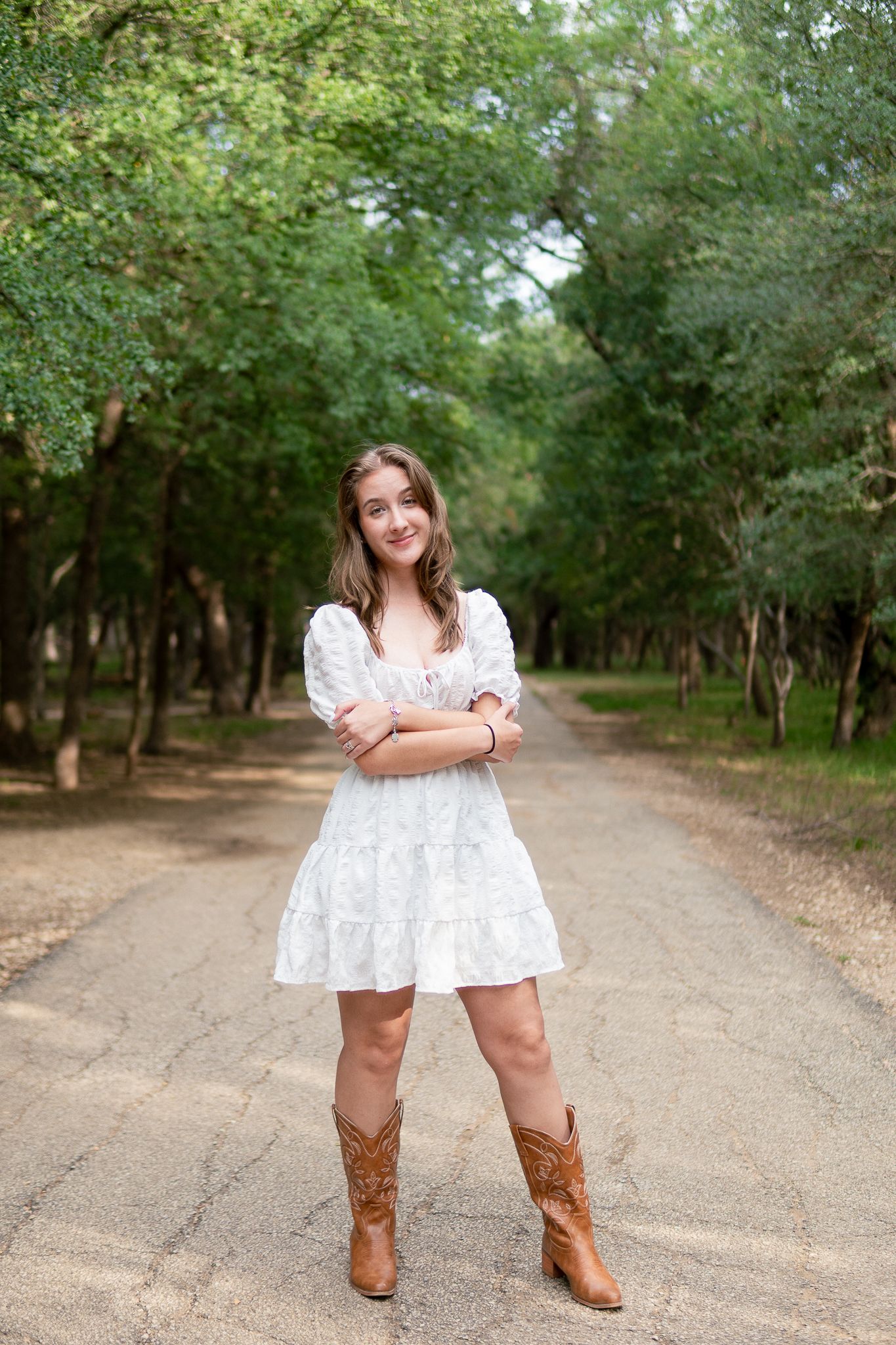 A dirt path through a green wooded area with brown cowboy boots and a white dress visible in the scene.