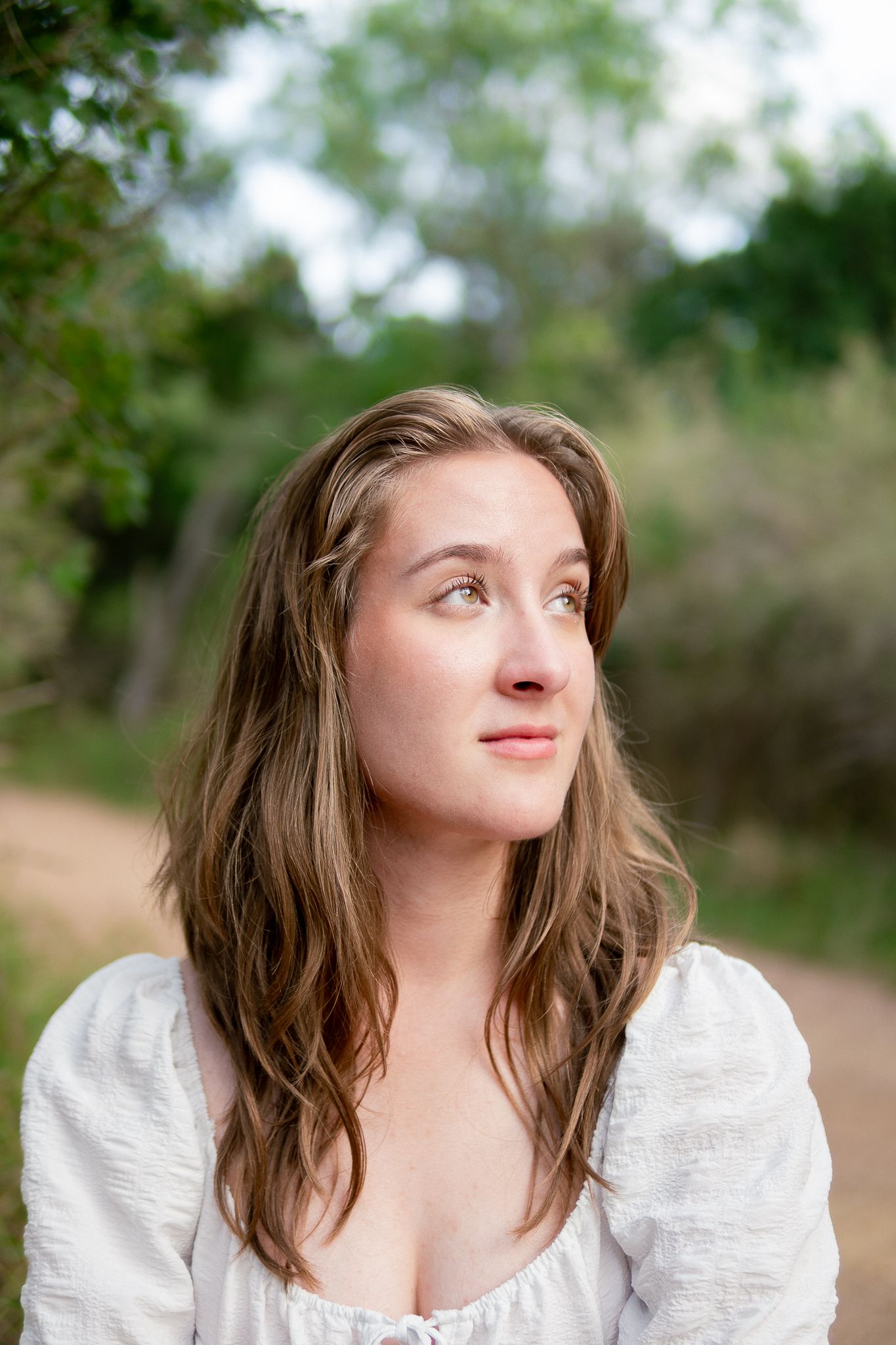 A series of outdoor portrait photos showing someone in a white blouse looking upward with natural lighting and foliage background.