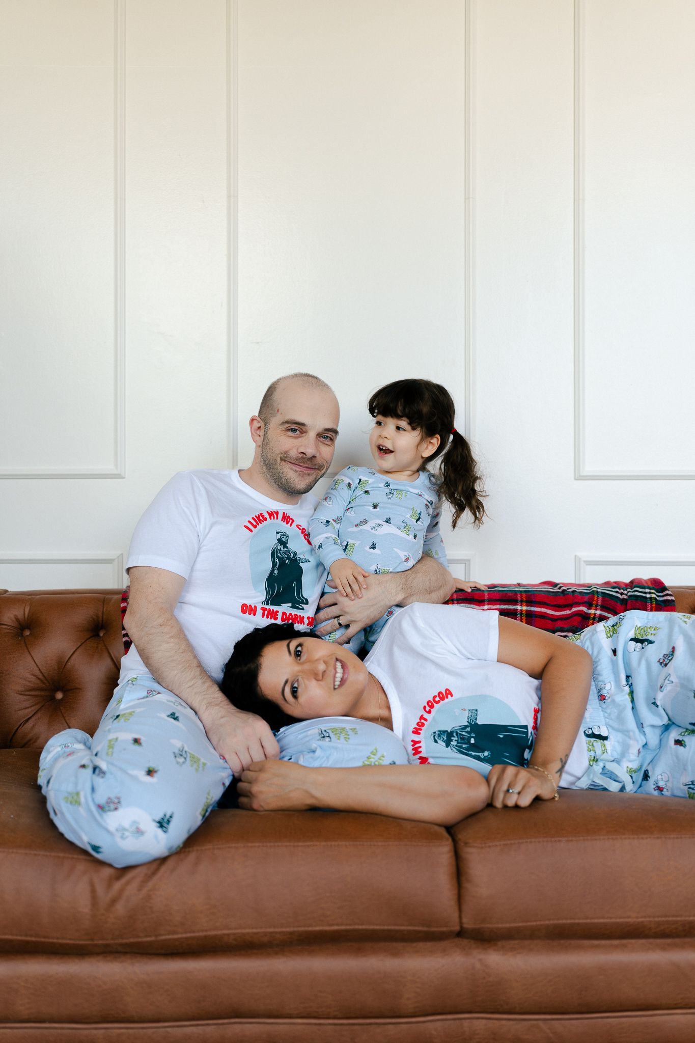 Two people share a playful moment while relaxing together on a brown leather couch.