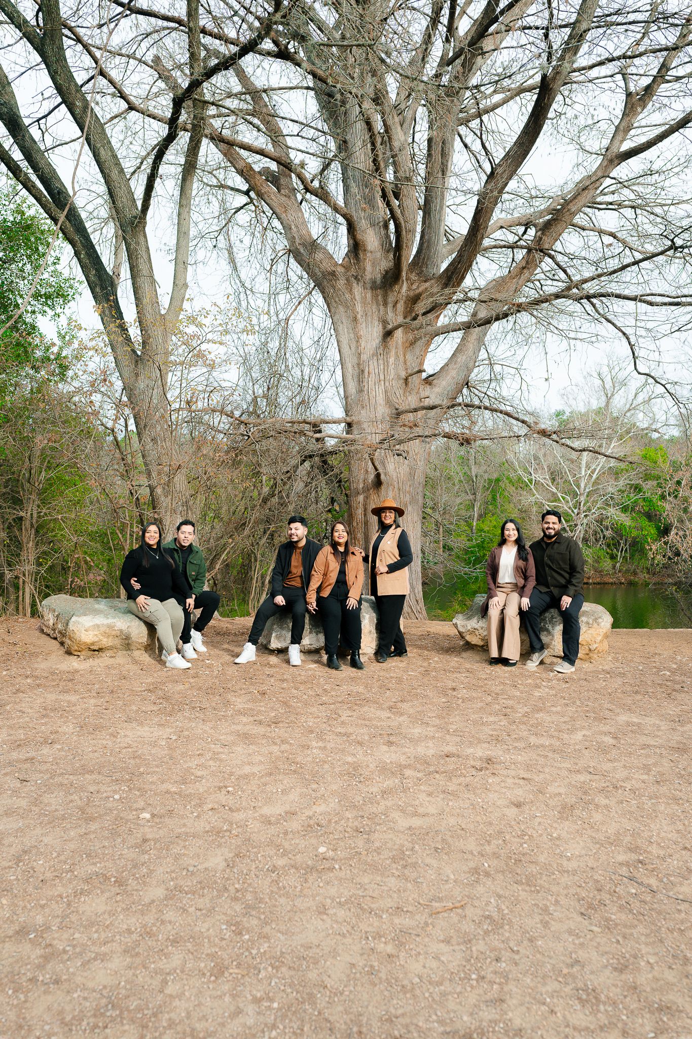 Group photo session outdoors with a large tree trunk and bare branches in winter setting.