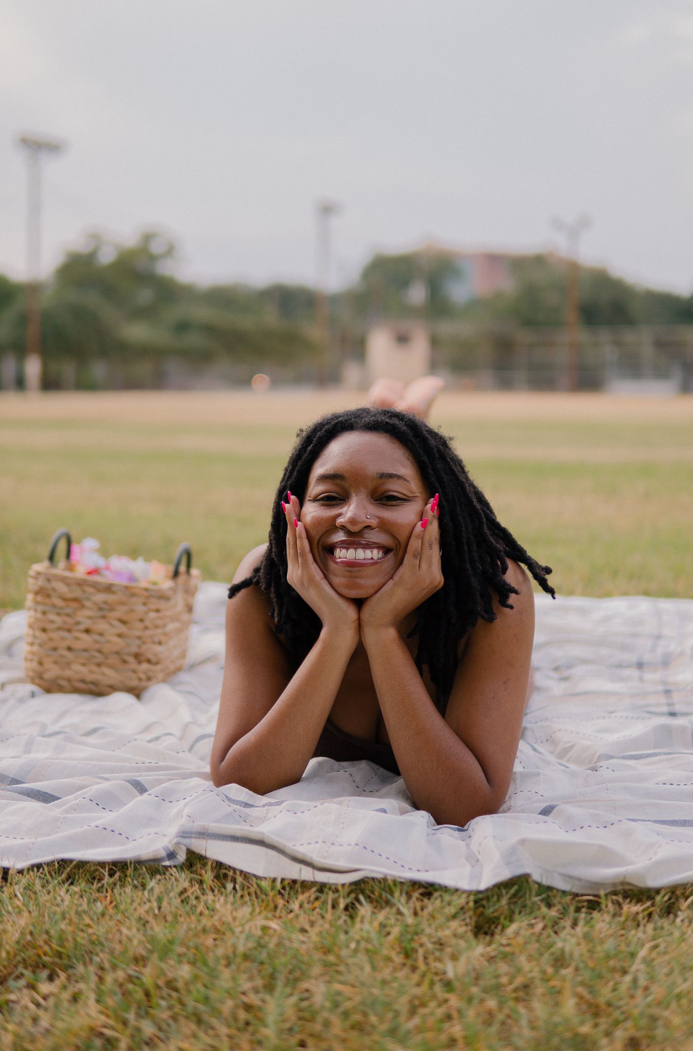 Person lying on a white blanket outdoors on grass showing joyful expressions in a sequence of candid poses.