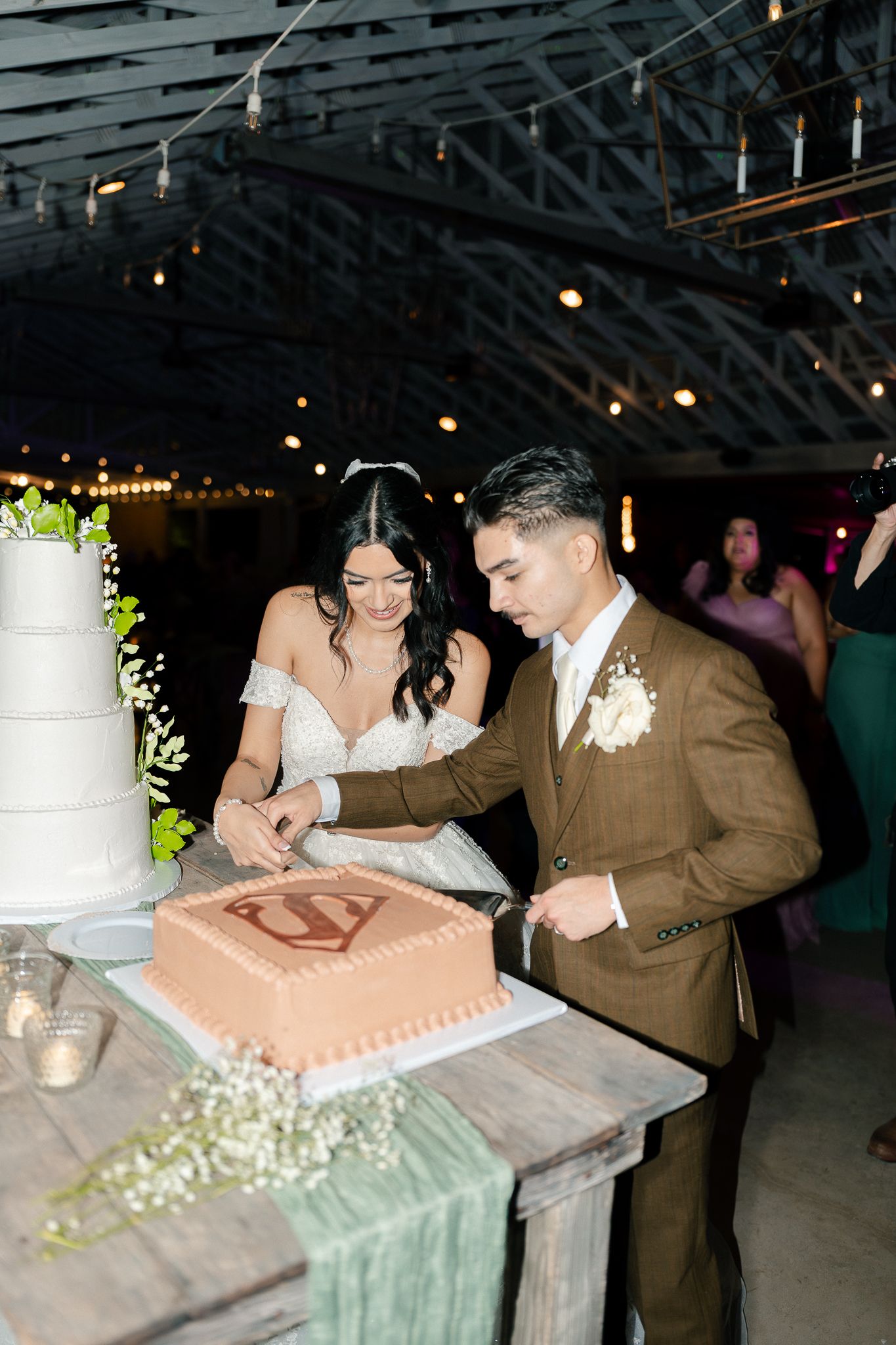 A couple signs their marriage license at a wedding reception venue with twinkling lights in the background.