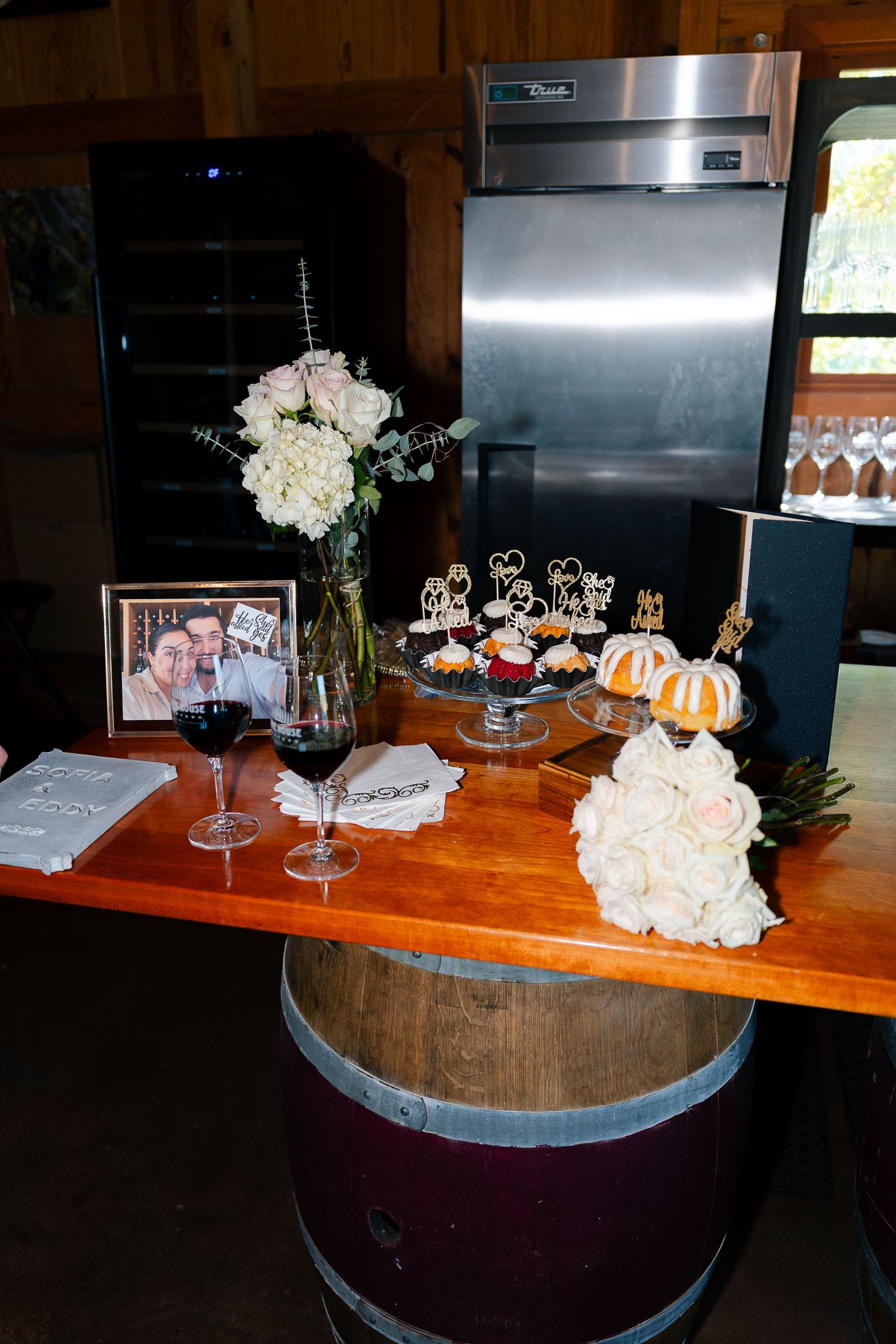 Wine barrel table decorated with white floral arrangements and pumpkins for an elegant autumn event setup.