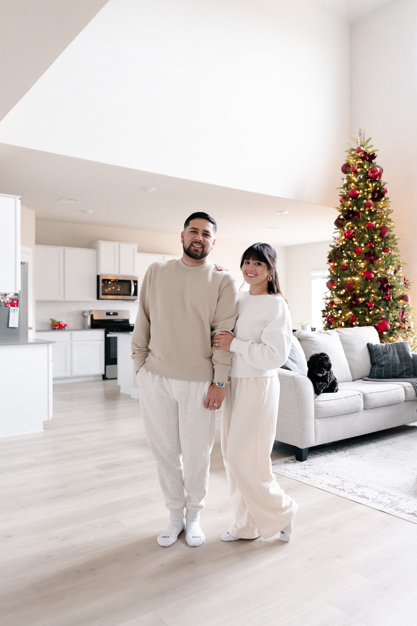 Bright modern living room decorated for Christmas with a lit tree and light wood flooring.