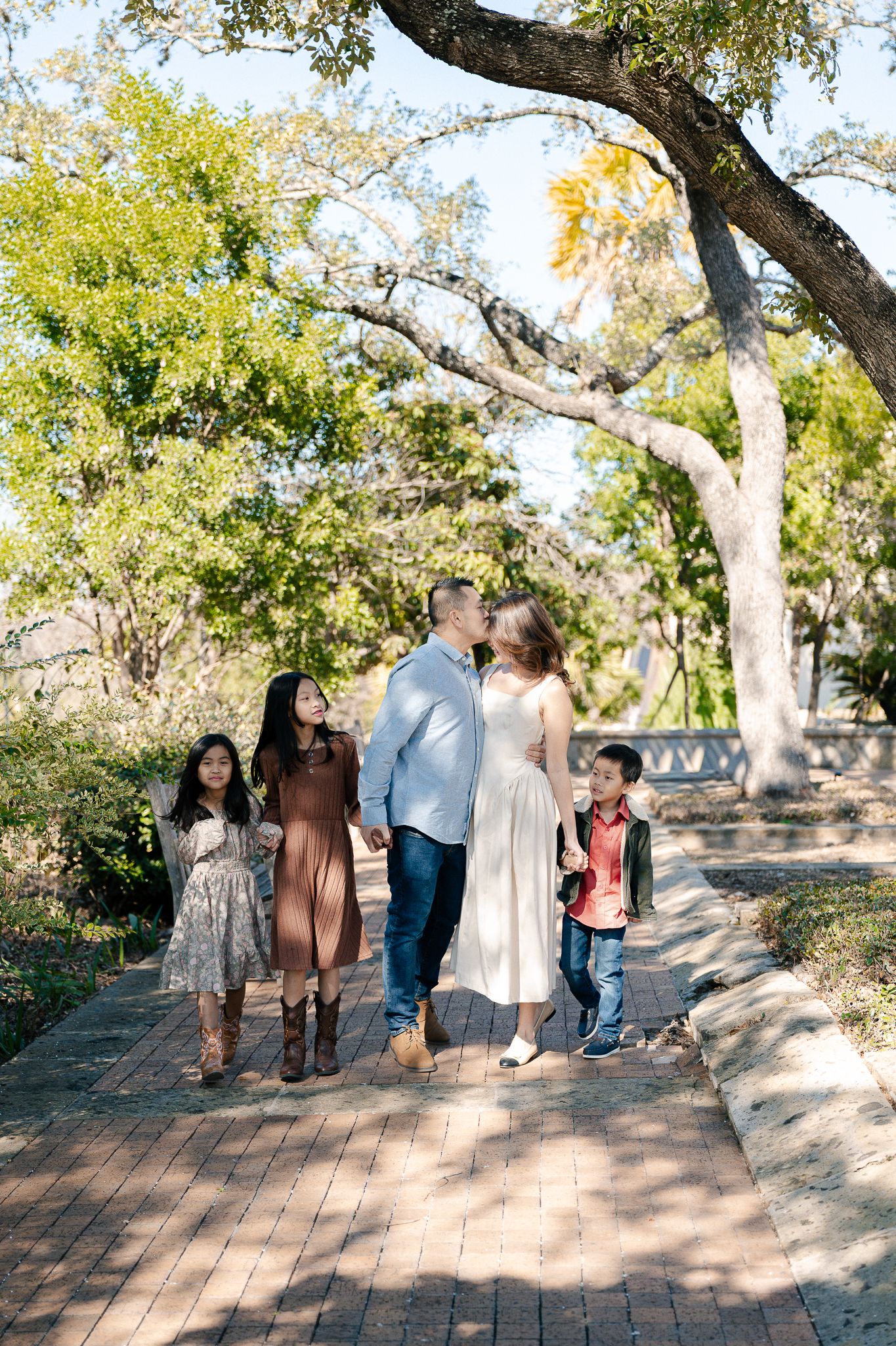 Family walking together on a wooden boardwalk path through a scenic park on a sunny autumn day.