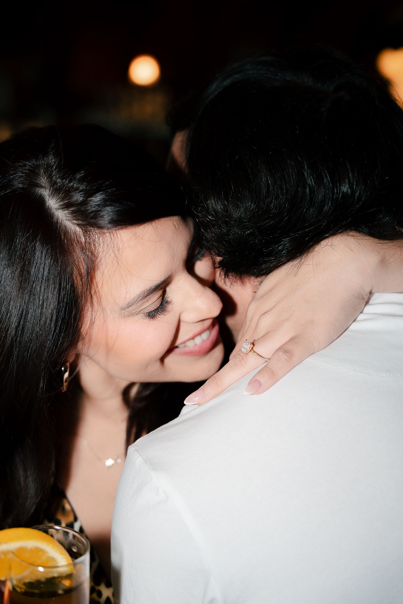 A tender romantic moment captured in black and white as two people share a gentle kiss in soft lighting.