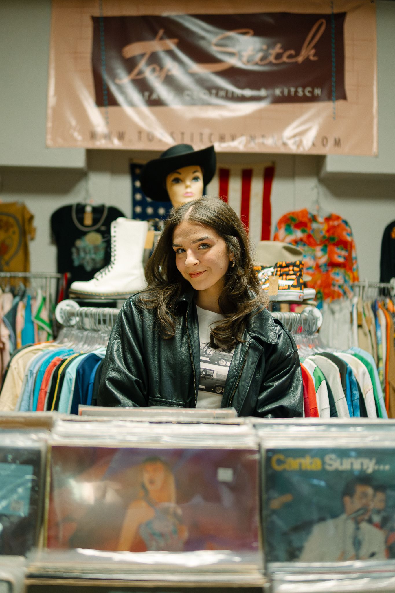 A customer browses through vinyl records at a retail store with American flags and clothing displays visible in background.