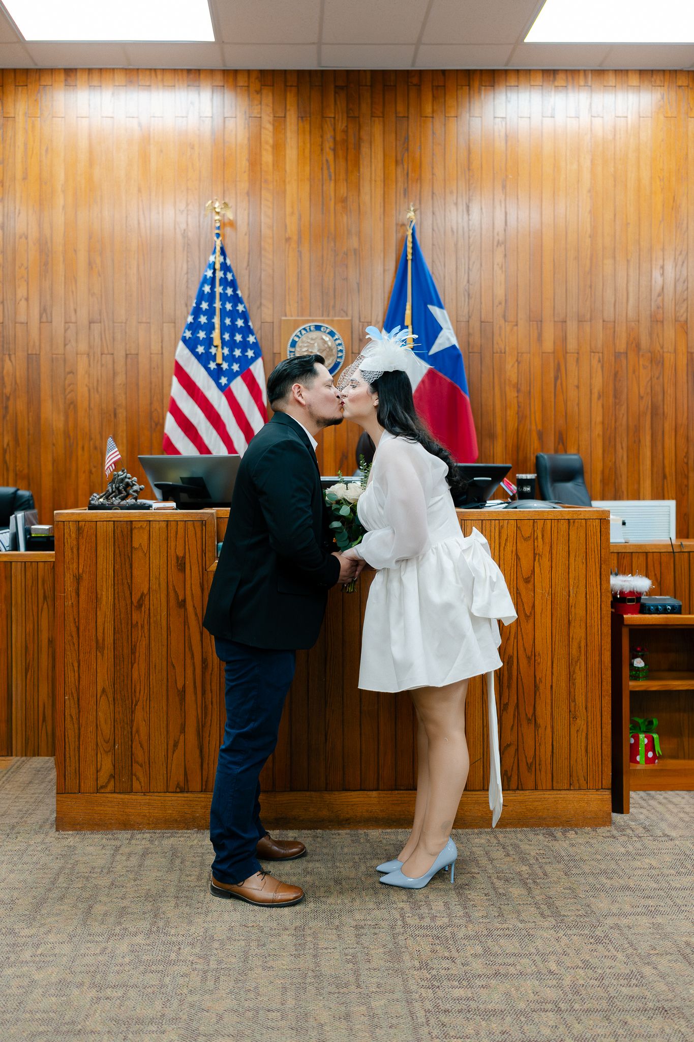 A series of five photos showing a couple exchanging vows during a courthouse wedding ceremony with flags in background.