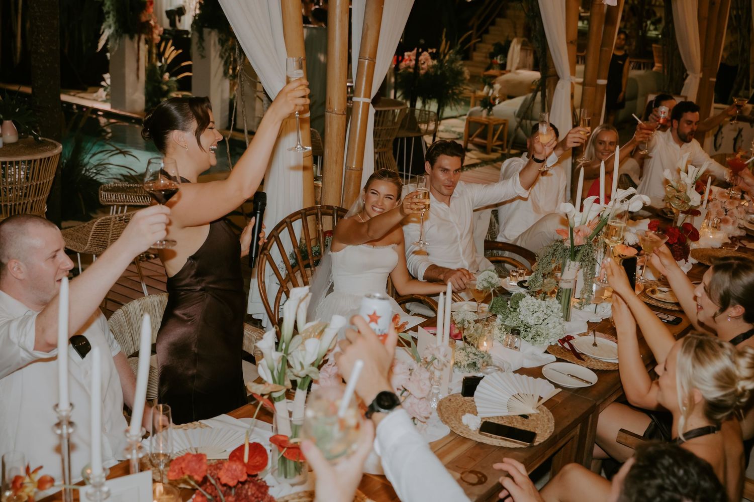 Wedding guests raising glasses in a joyful toast at a festive reception dinner.