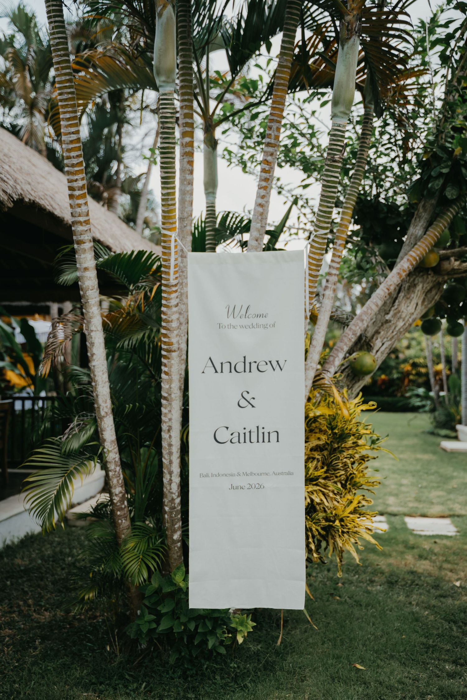Wedding welcome sign for Andrew and Caitlin surrounded by tropical palms.