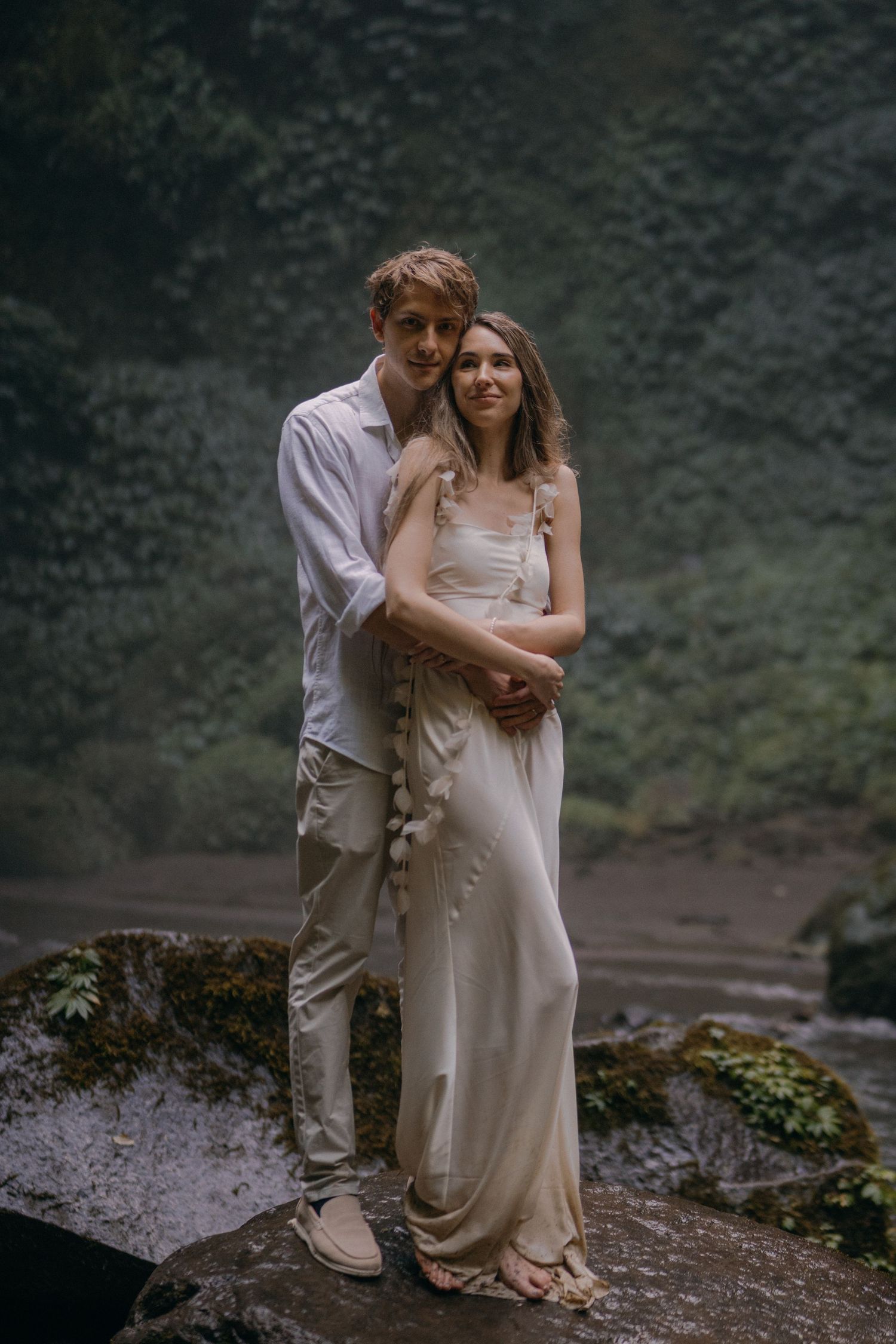 A romantic couple embraces on a misty cliffside during an intimate outdoor photoshoot in nature.