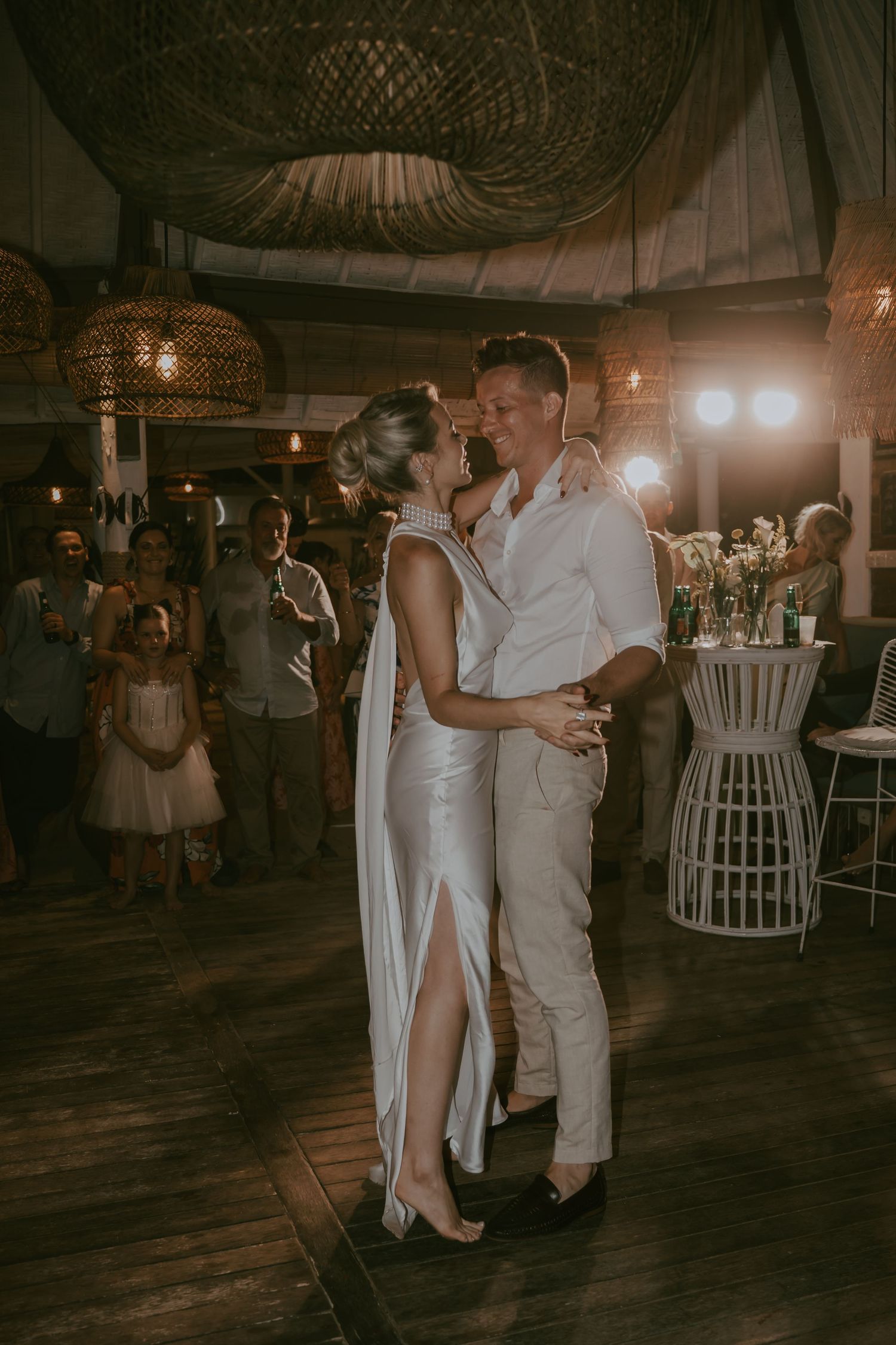 Romantic dance moment under woven pendant lights at tropical wedding reception.