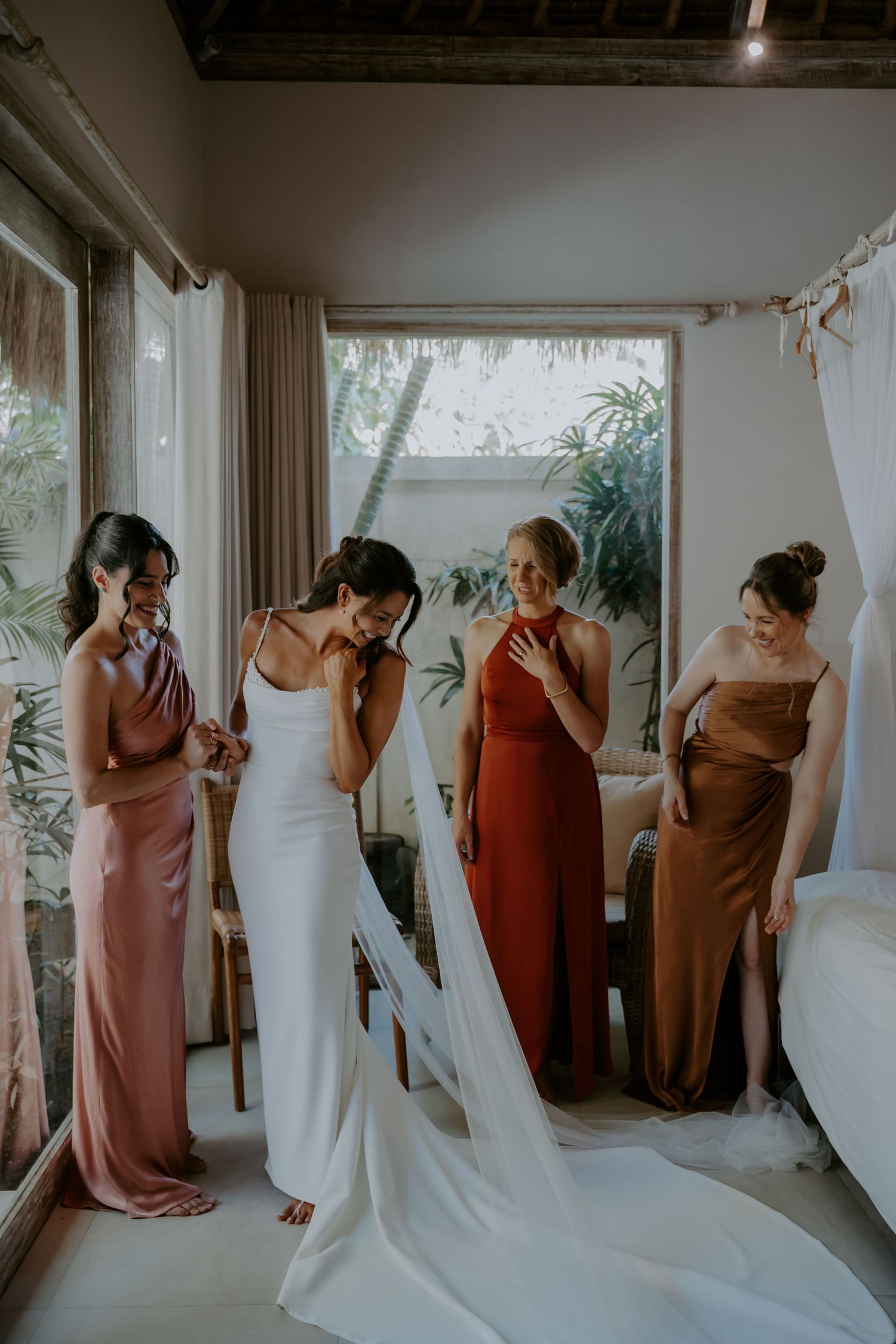 An emotional wedding scene unfolds in a bright sunlit room with people wearing burgundy dresses and a white wedding gown.