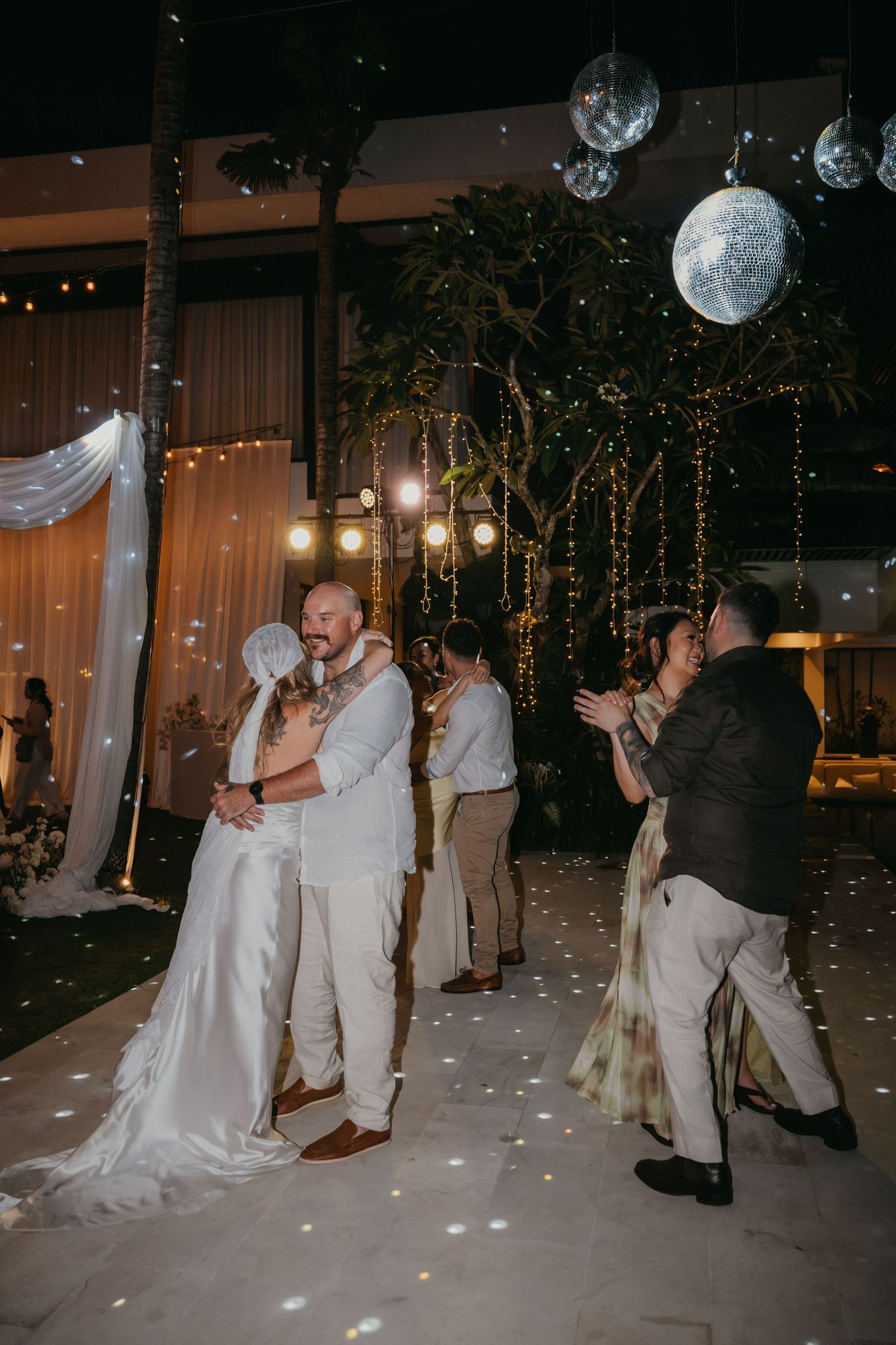 Bride and groom share first dance under glowing moon decorations with bubbles at elegant night reception.