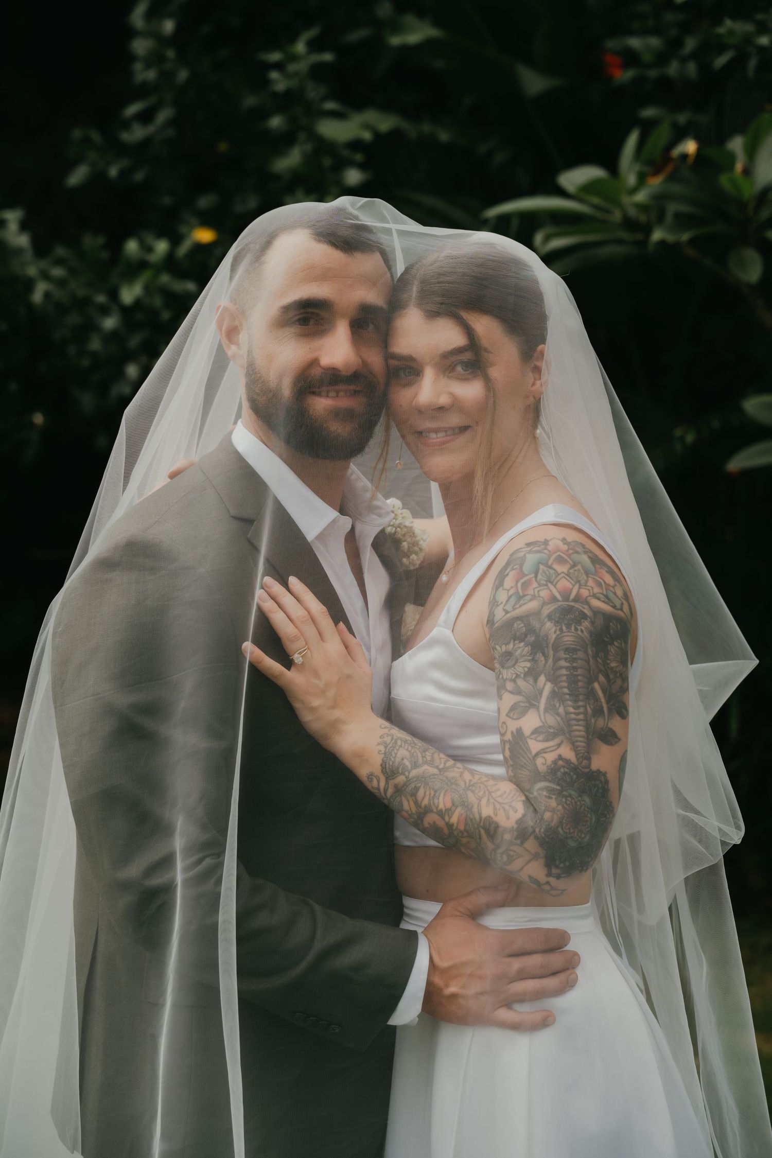 Bride and groom share tender moment under flowing wedding veil.