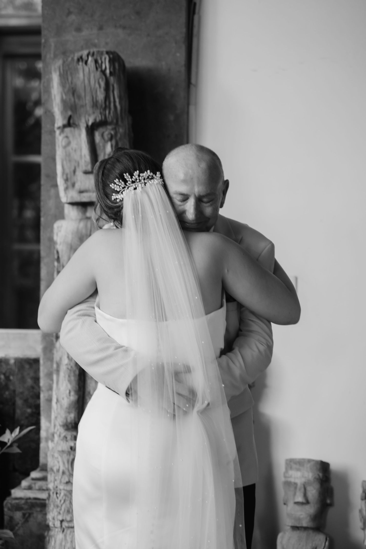 Black and white photo of a bride and groom sharing an emotional embrace on their wedding day.