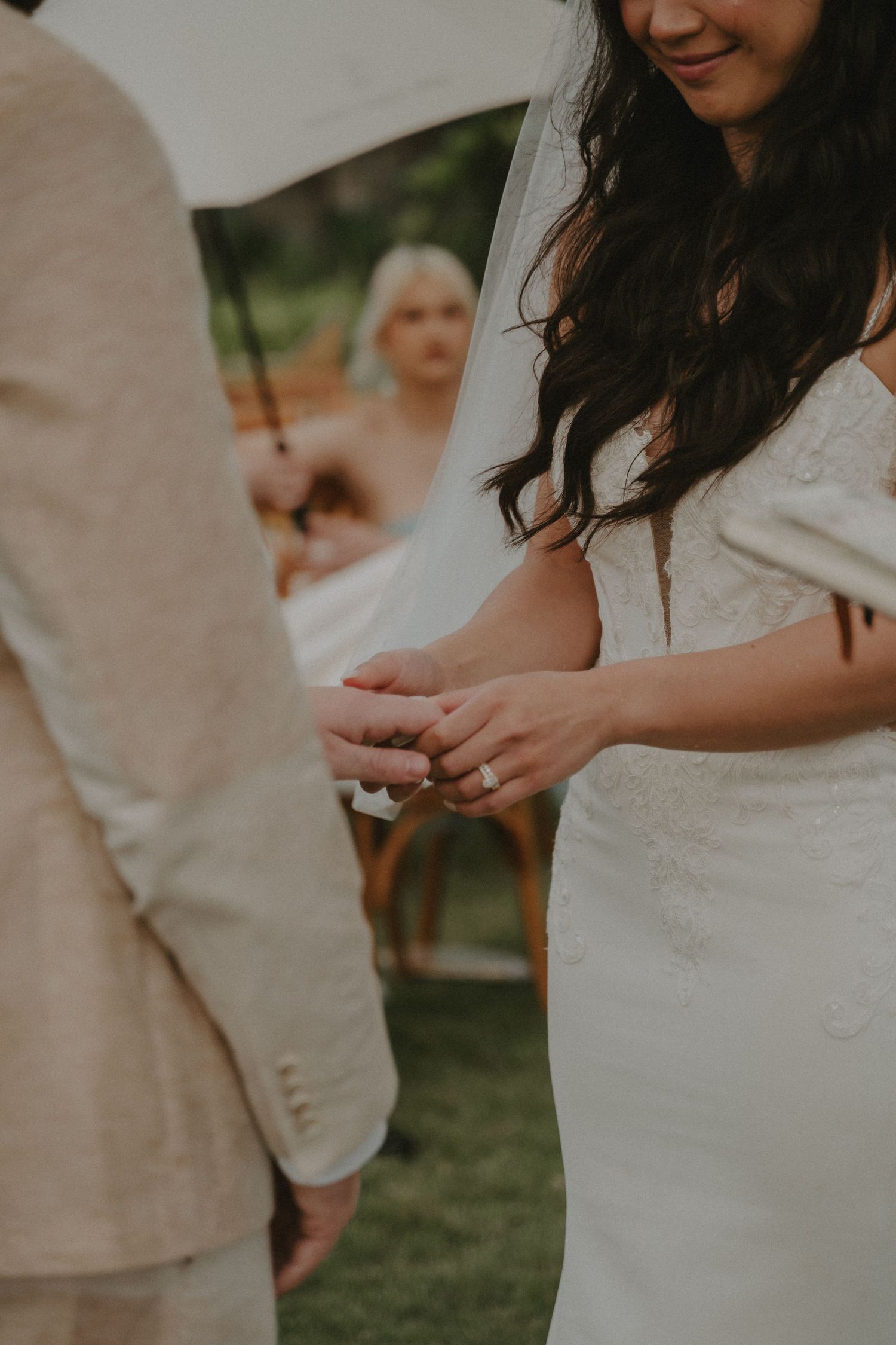 A close-up detail shot of a white lace wedding dress with delicate embroidery patterns.