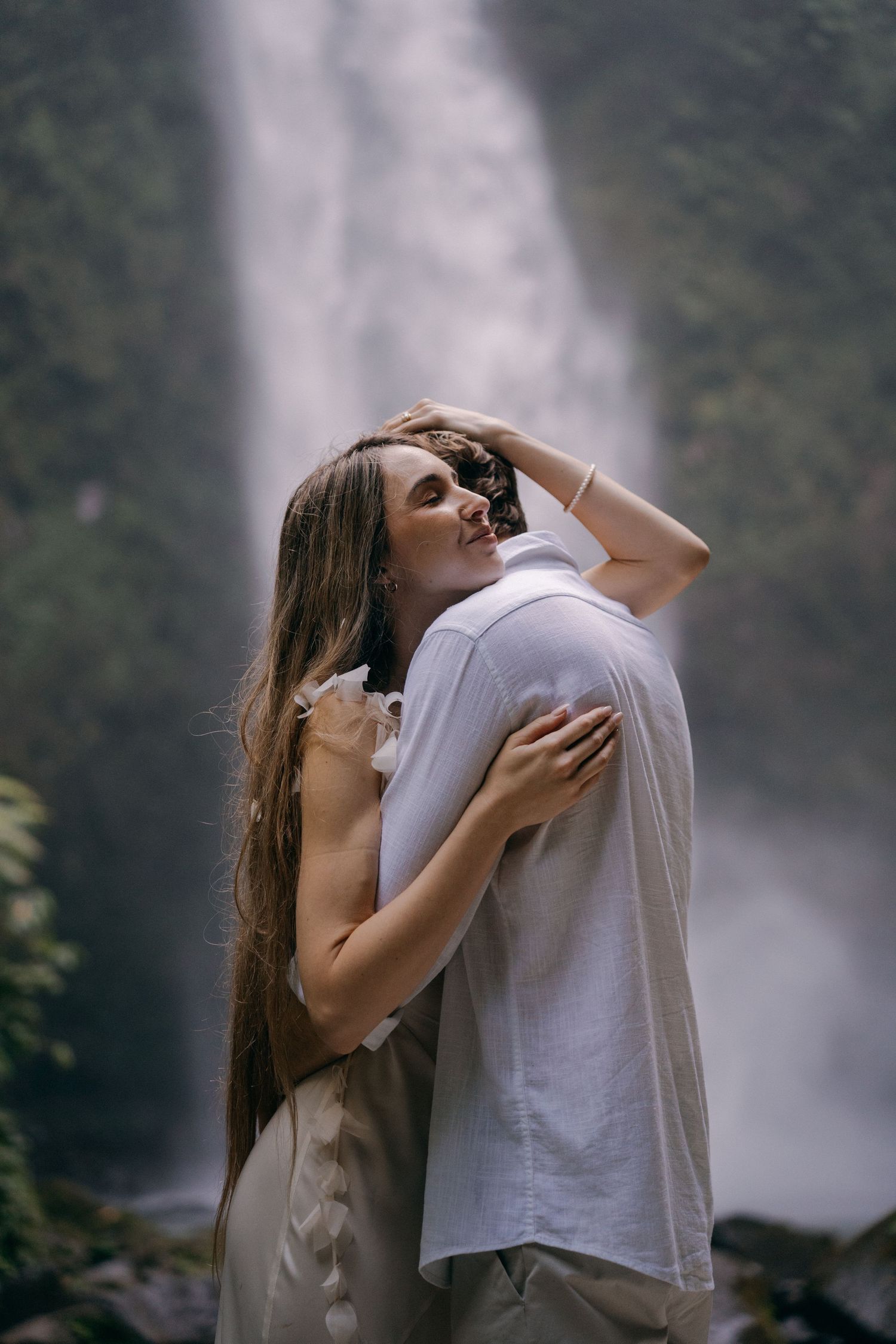 A couple embraces passionately in a series of intimate photos against a misty waterfall backdrop.