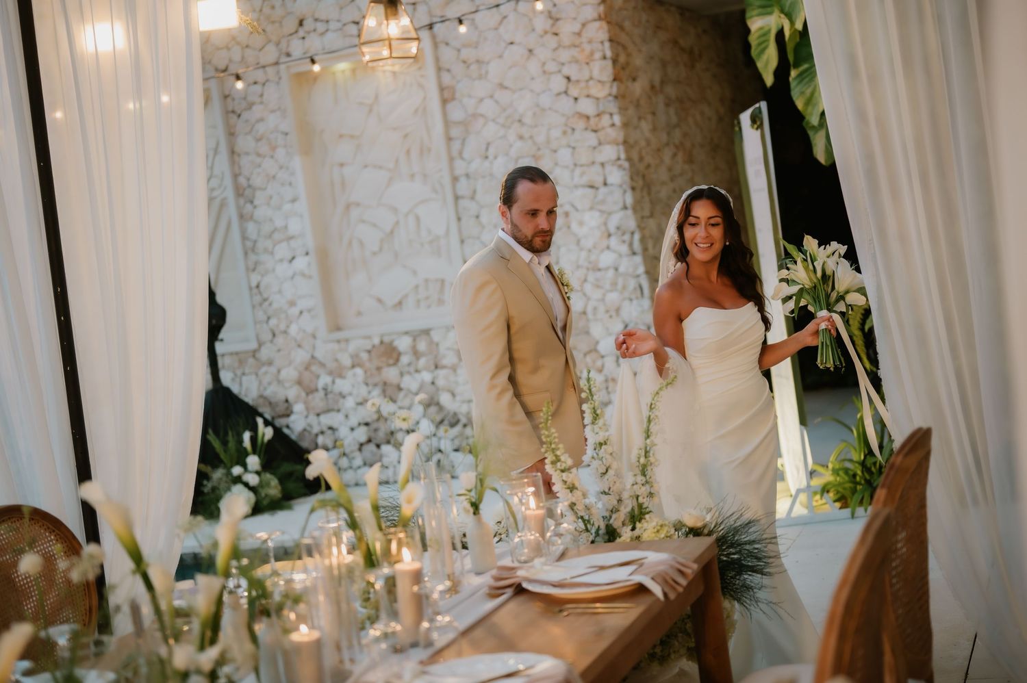 Newlyweds walk hand in hand into beautifully decorated reception venue with floral arrangements.