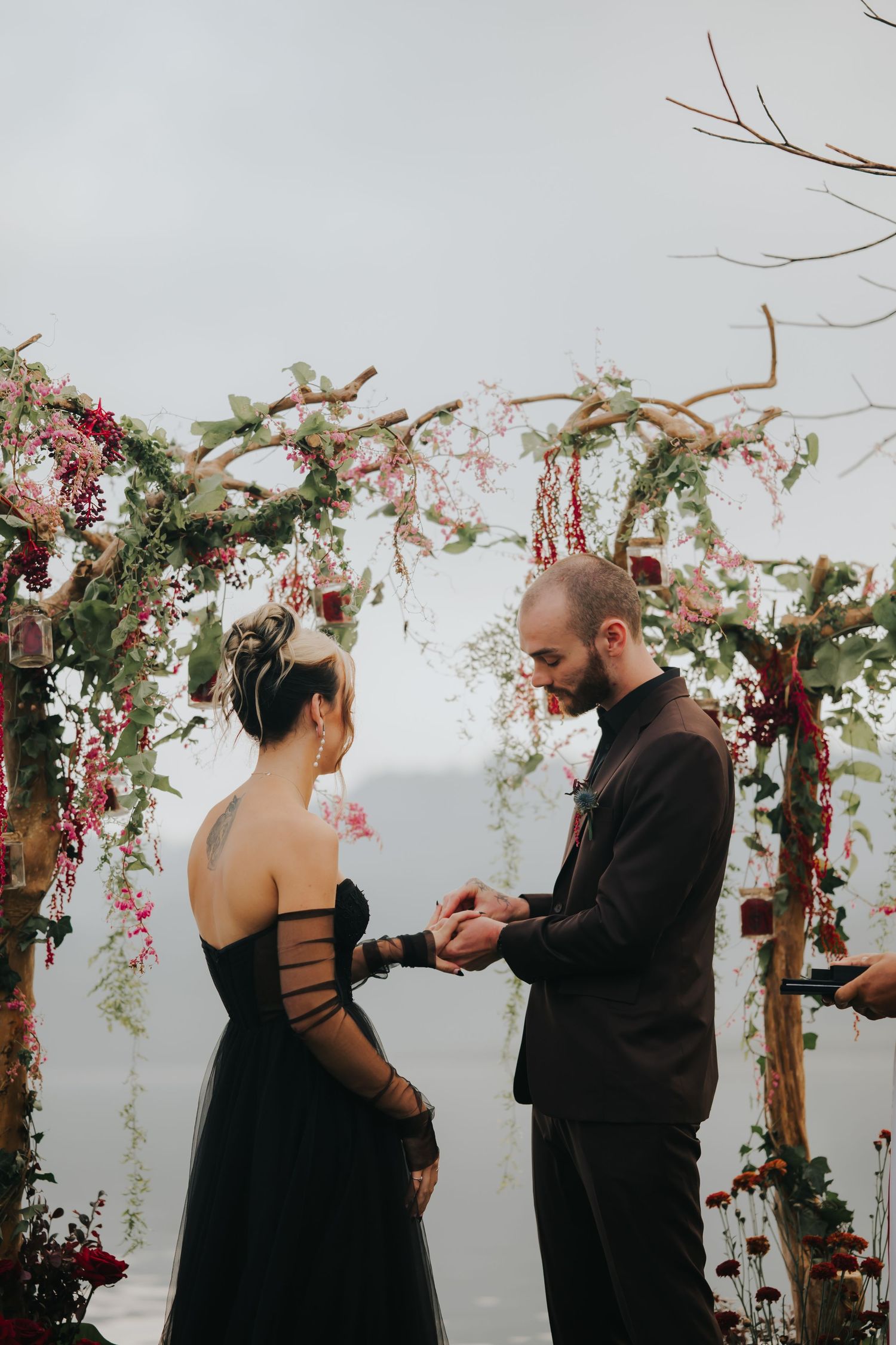 An intimate wedding ceremony moment under an arch decorated with cascading flowers.