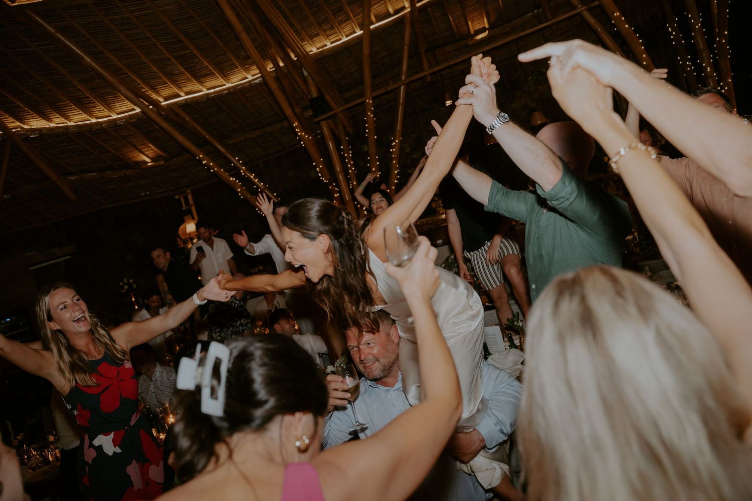 Wedding reception guests dance and celebrate on a dimly lit dance floor during an evening party celebration.