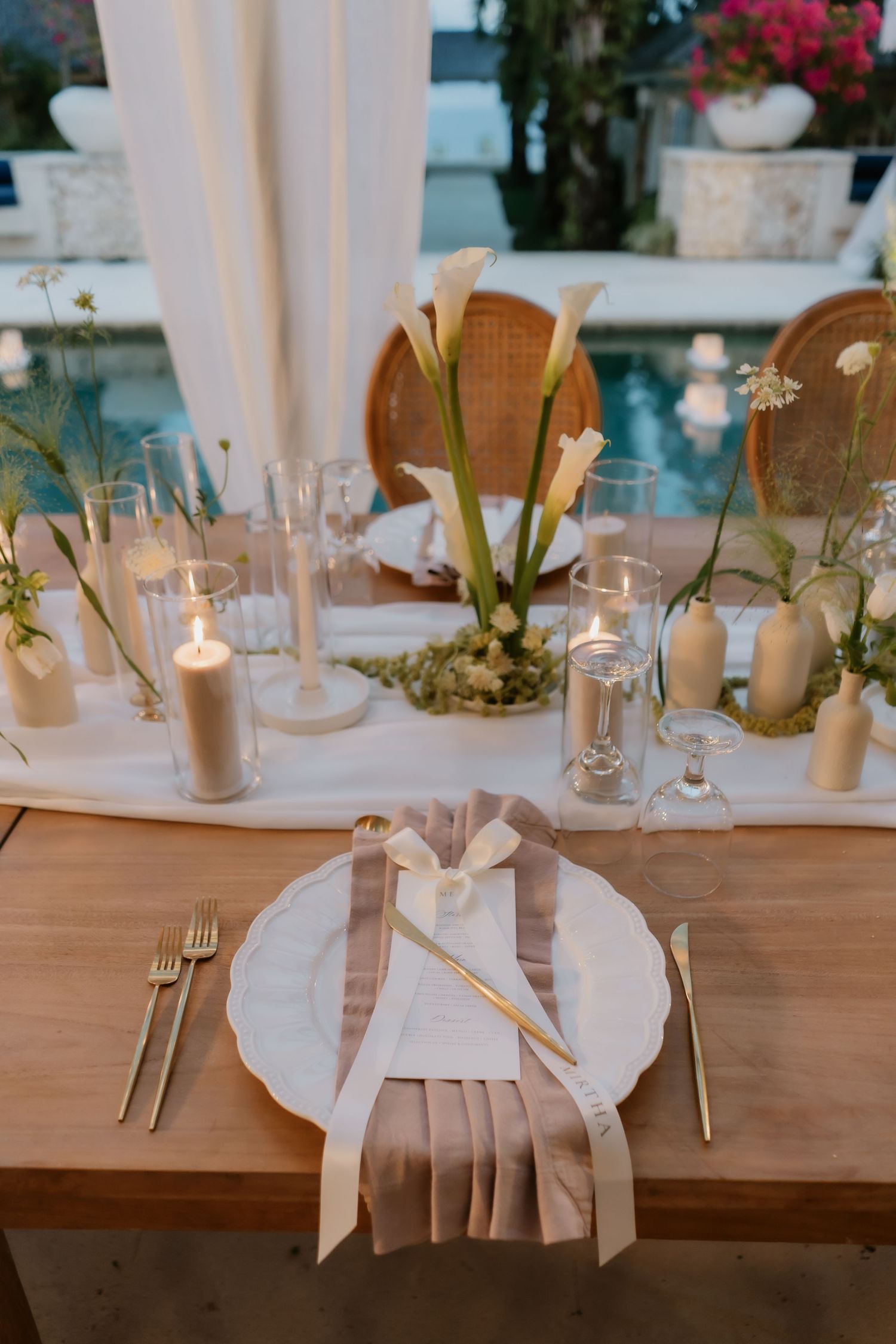 Elegant wedding table setting with calla lilies, candles, and gold cutlery.