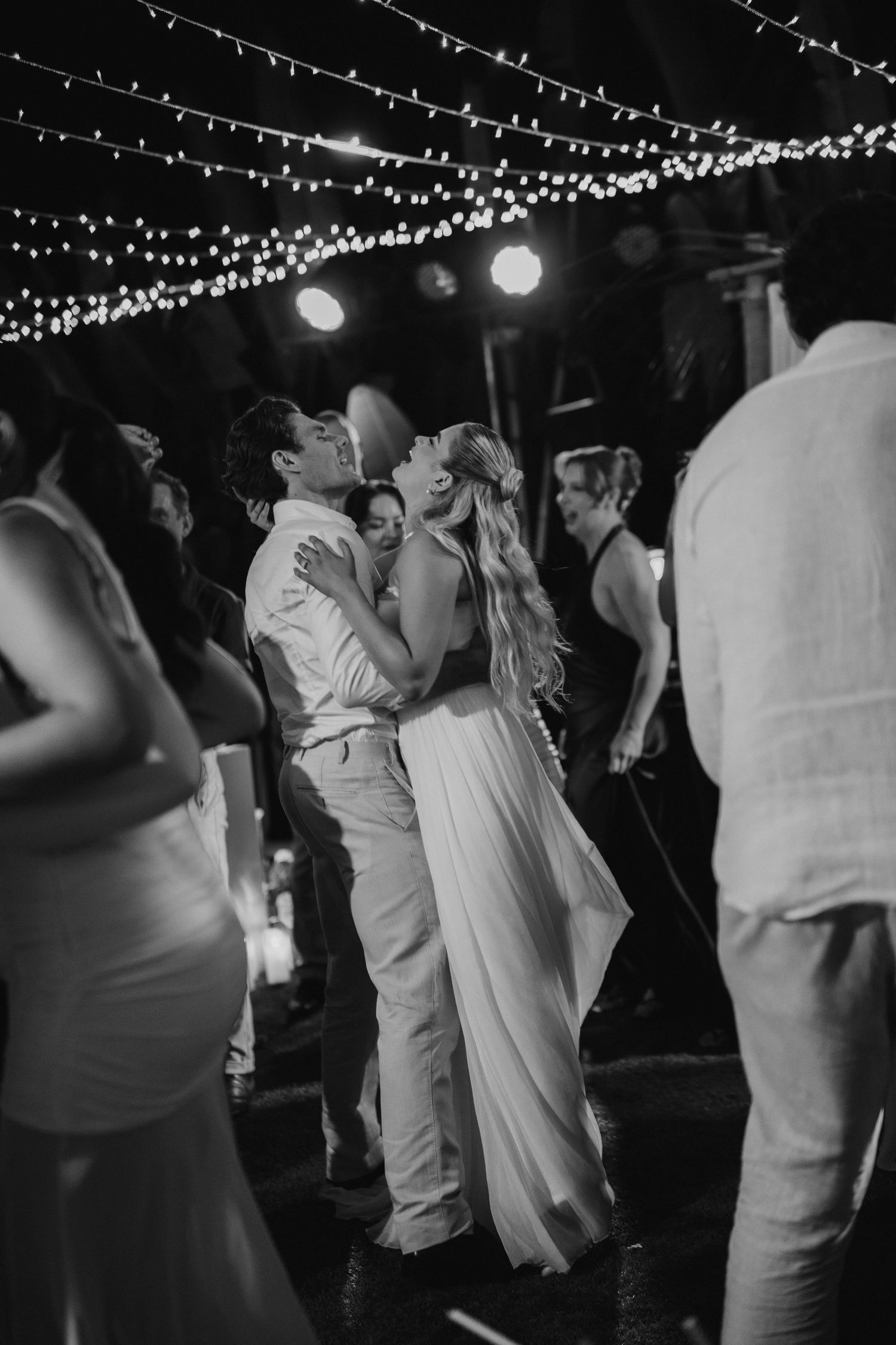 Black and white photo of bride and groom sharing a kiss while dancing at wedding reception.
