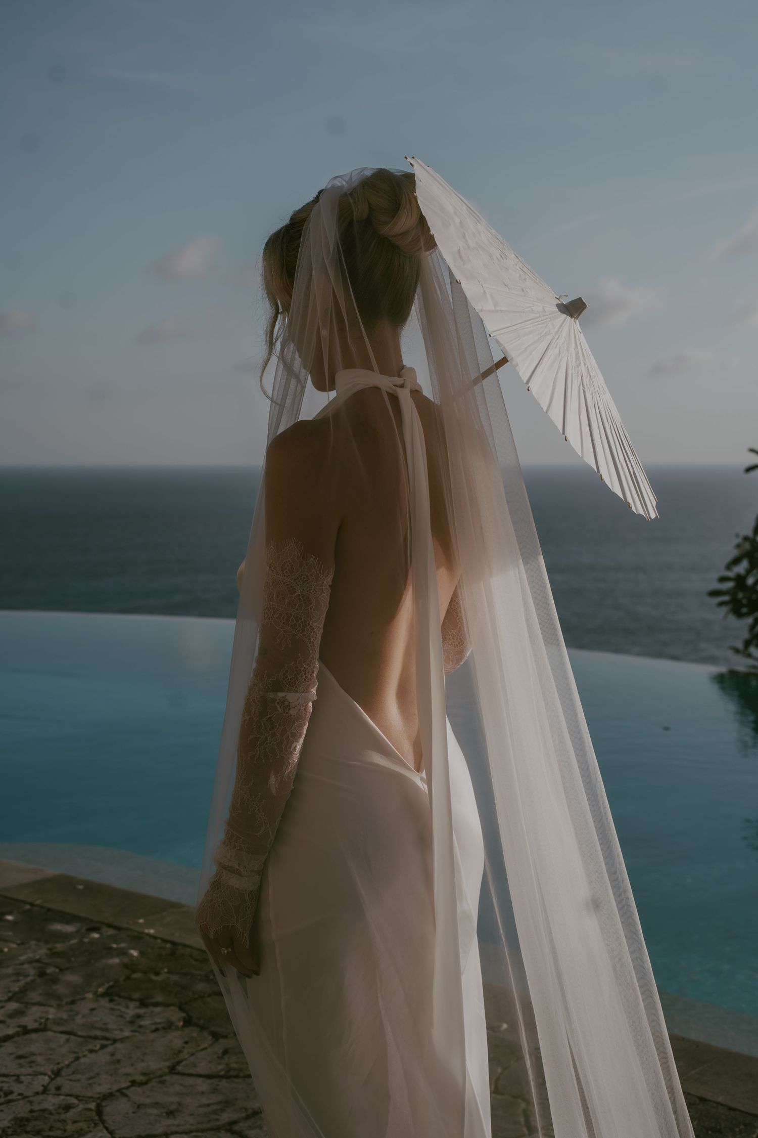 Ethereal bridal veils flow in the breeze against a dramatic ocean backdrop.