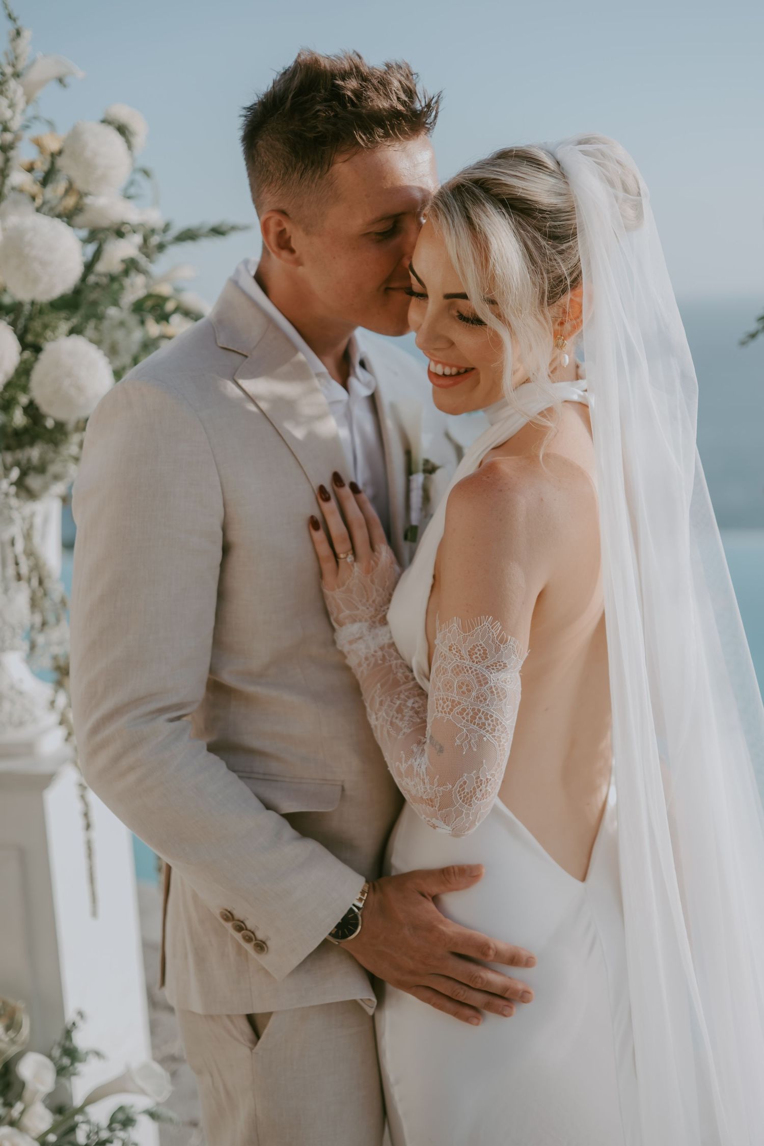 Romantic wedding couple embraces during intimate coastal ceremony.