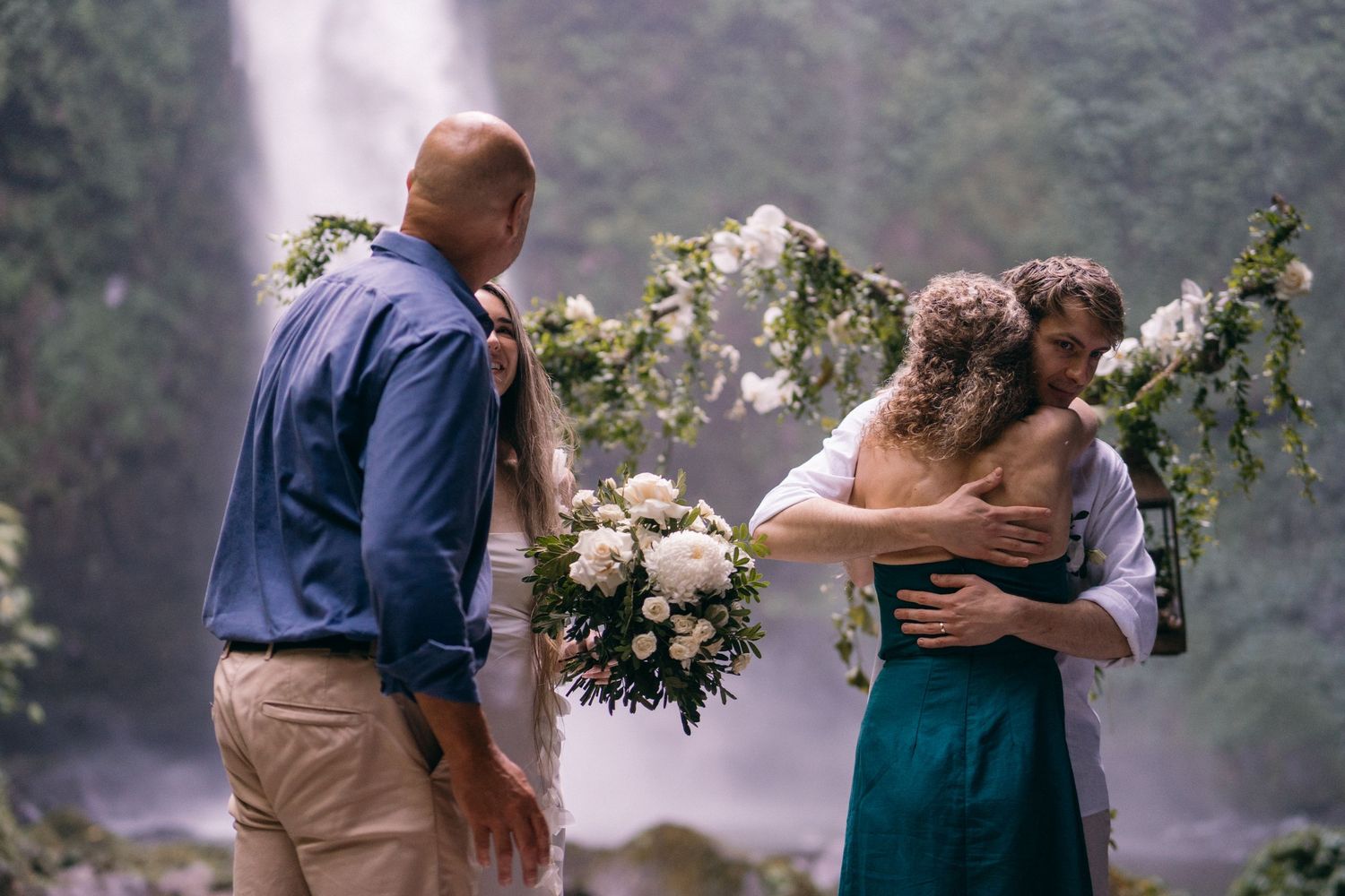 Romantic couple embraces in a misty garden setting while holding elegant floral bouquets.