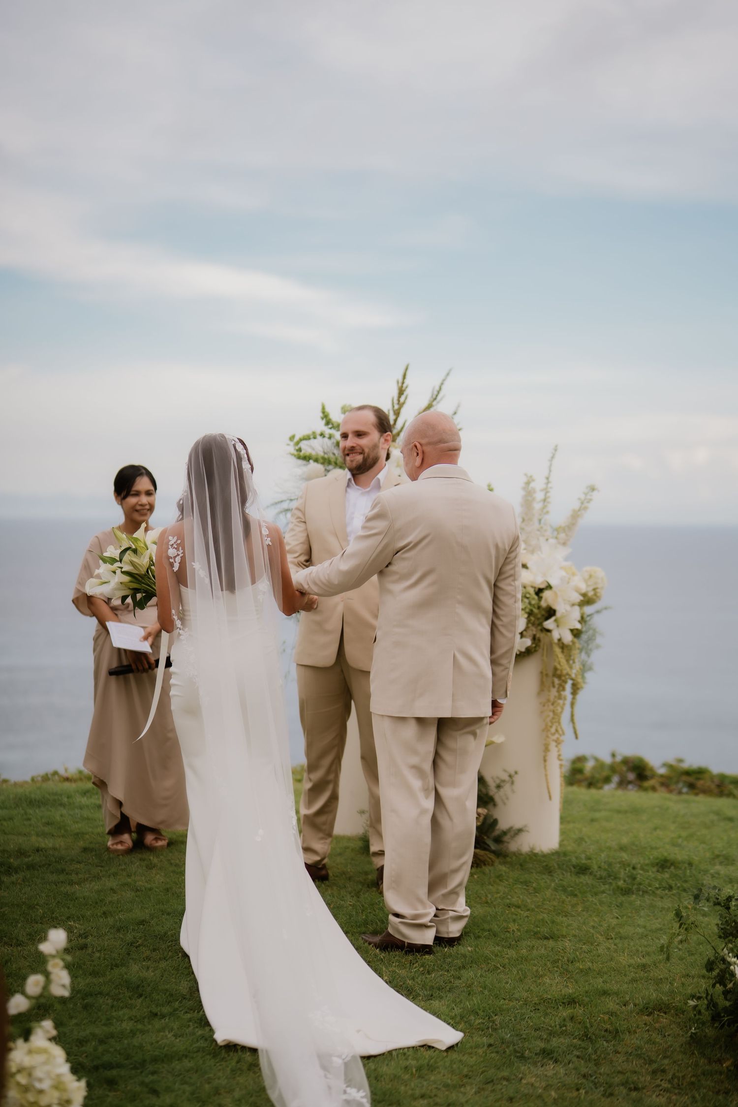 Bride and groom exchanging vows at outdoor cliffside ceremony overlooking the ocean.