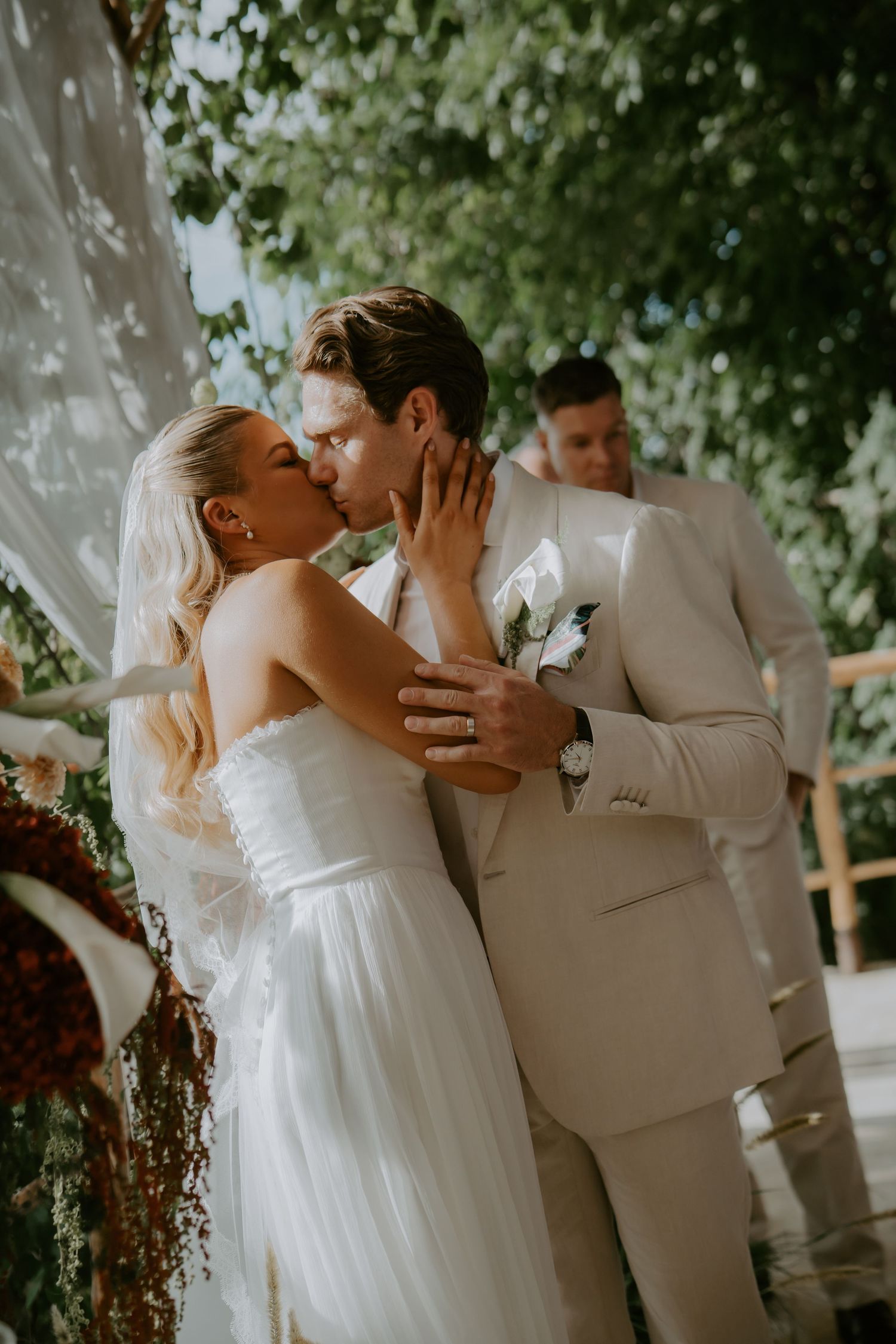 Bride and groom share their first kiss beneath a lush floral arch at the altar.