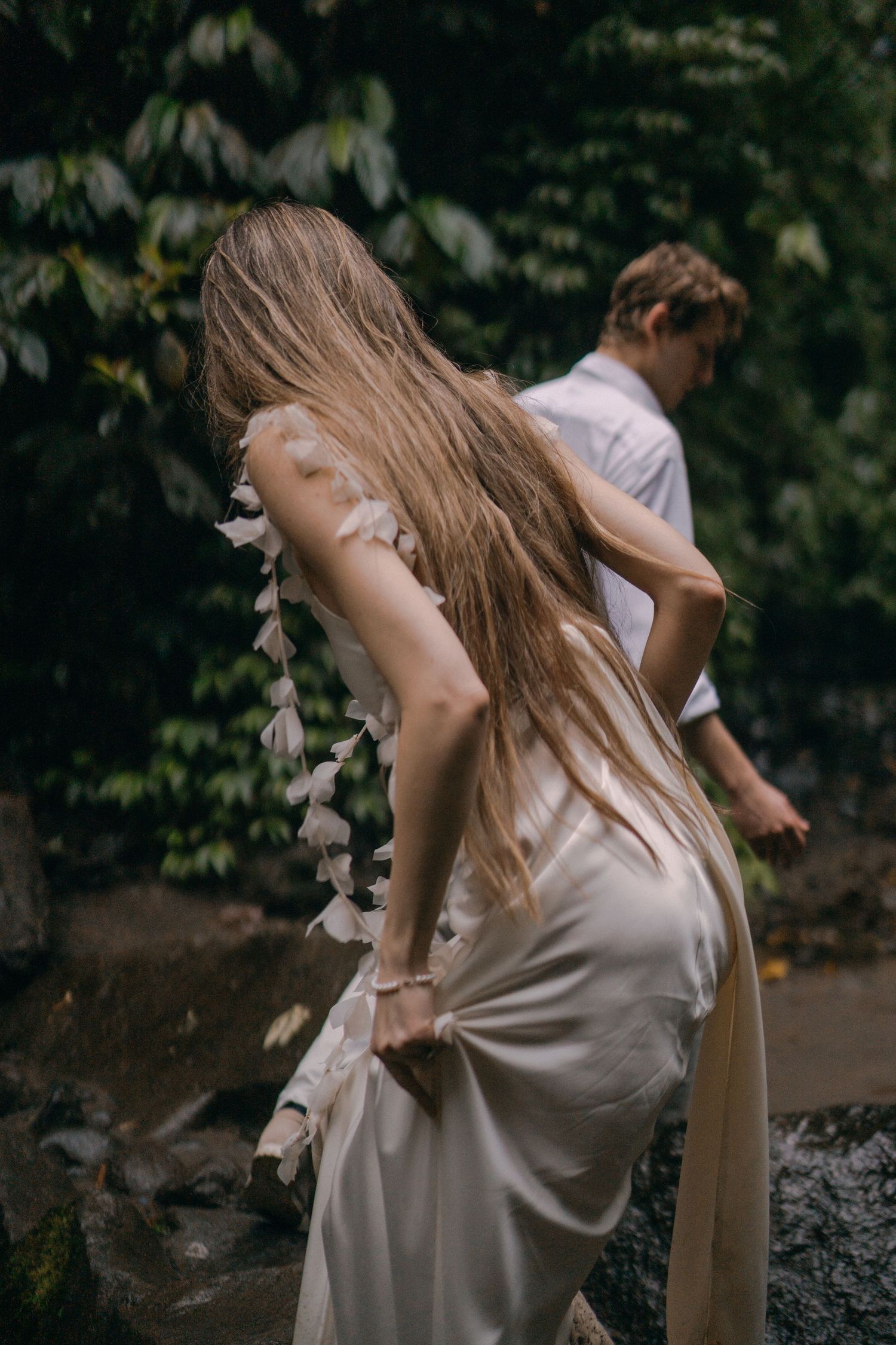 A sequence of ethereal dance movements captured in a moody forest setting with flowing white fabric in motion.