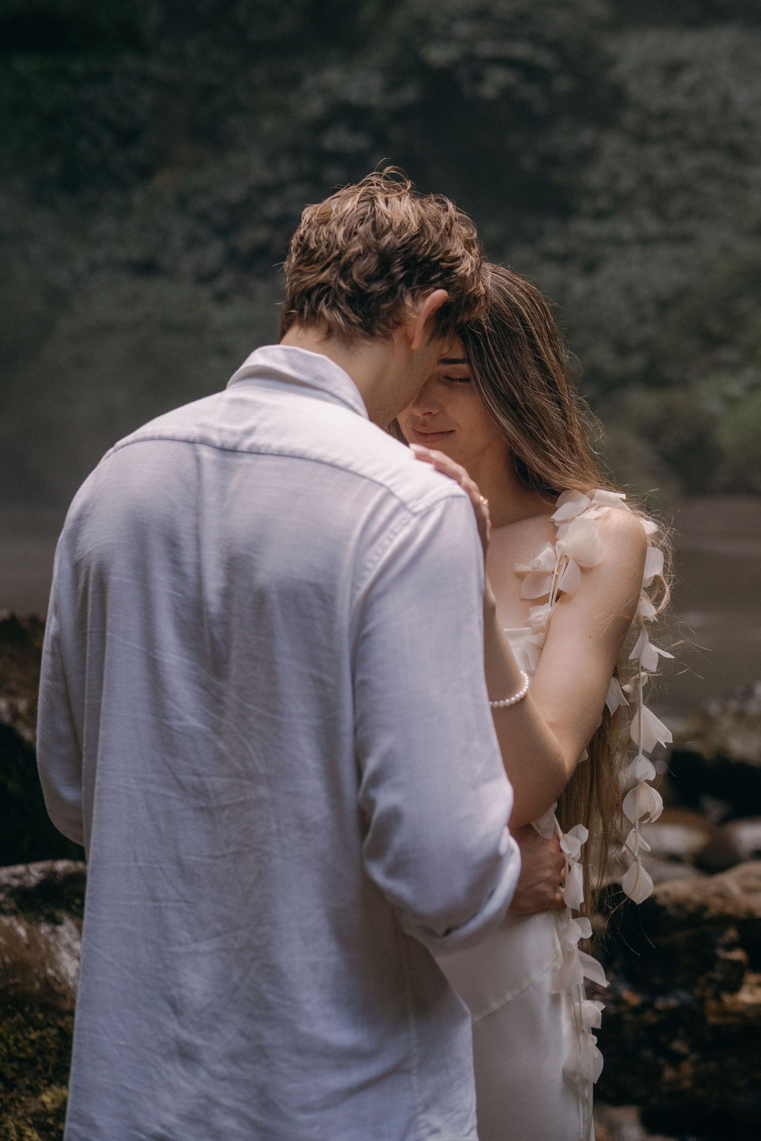 A romantic wedding couple shares intimate kisses in a sequence of black and white photographs by the coast.