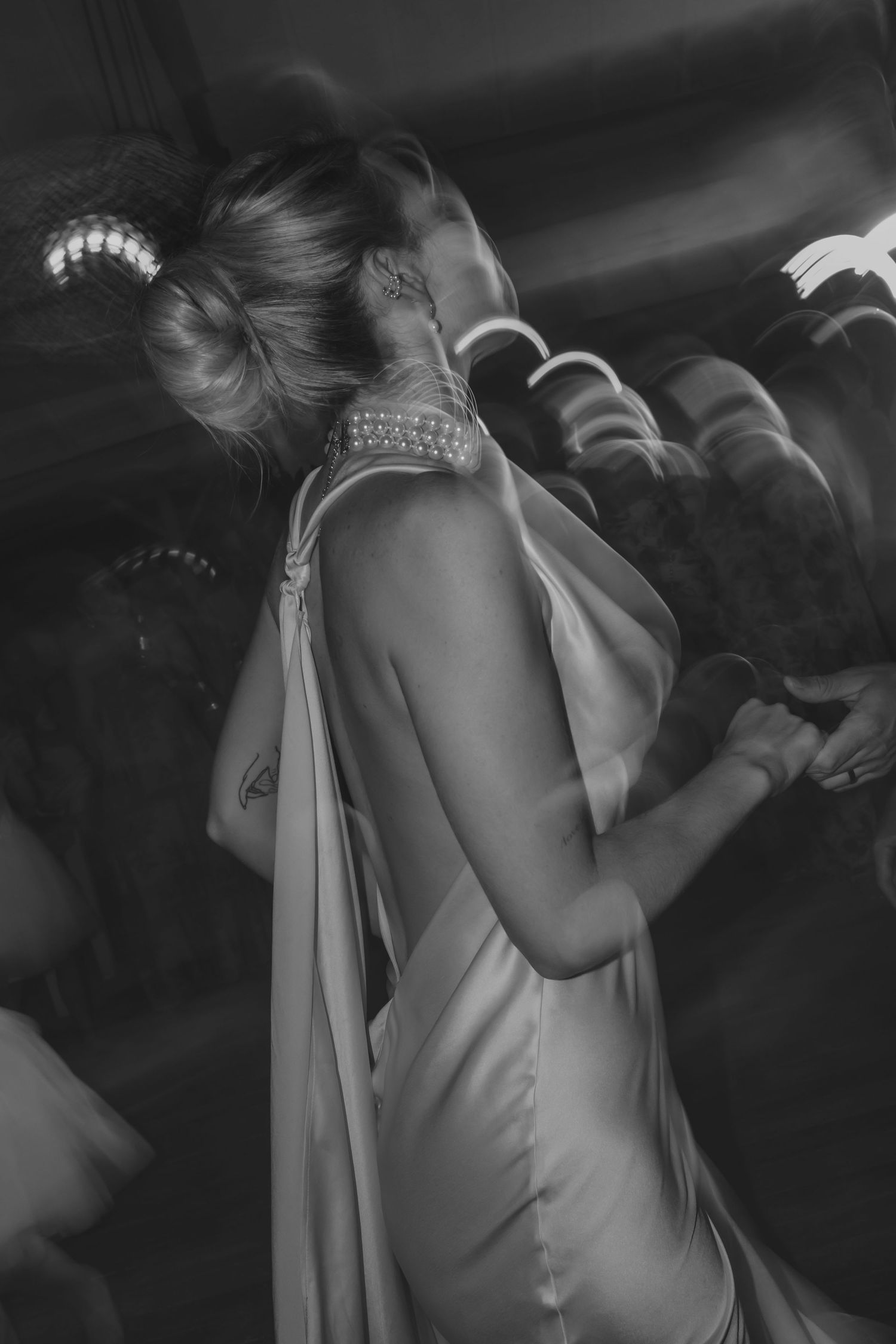 Artistic black and white shot of bride's elegant backless dress and jewelry.