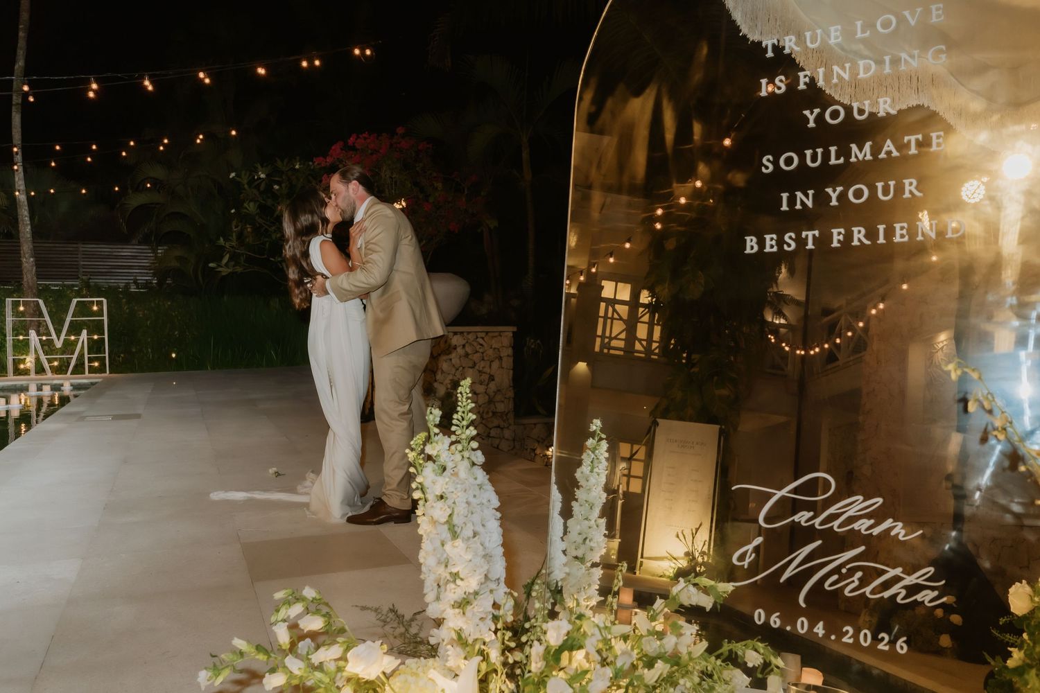 Newlyweds kiss beside personalized wedding sign reading Cullen and Martha dated 06.04.2024.
