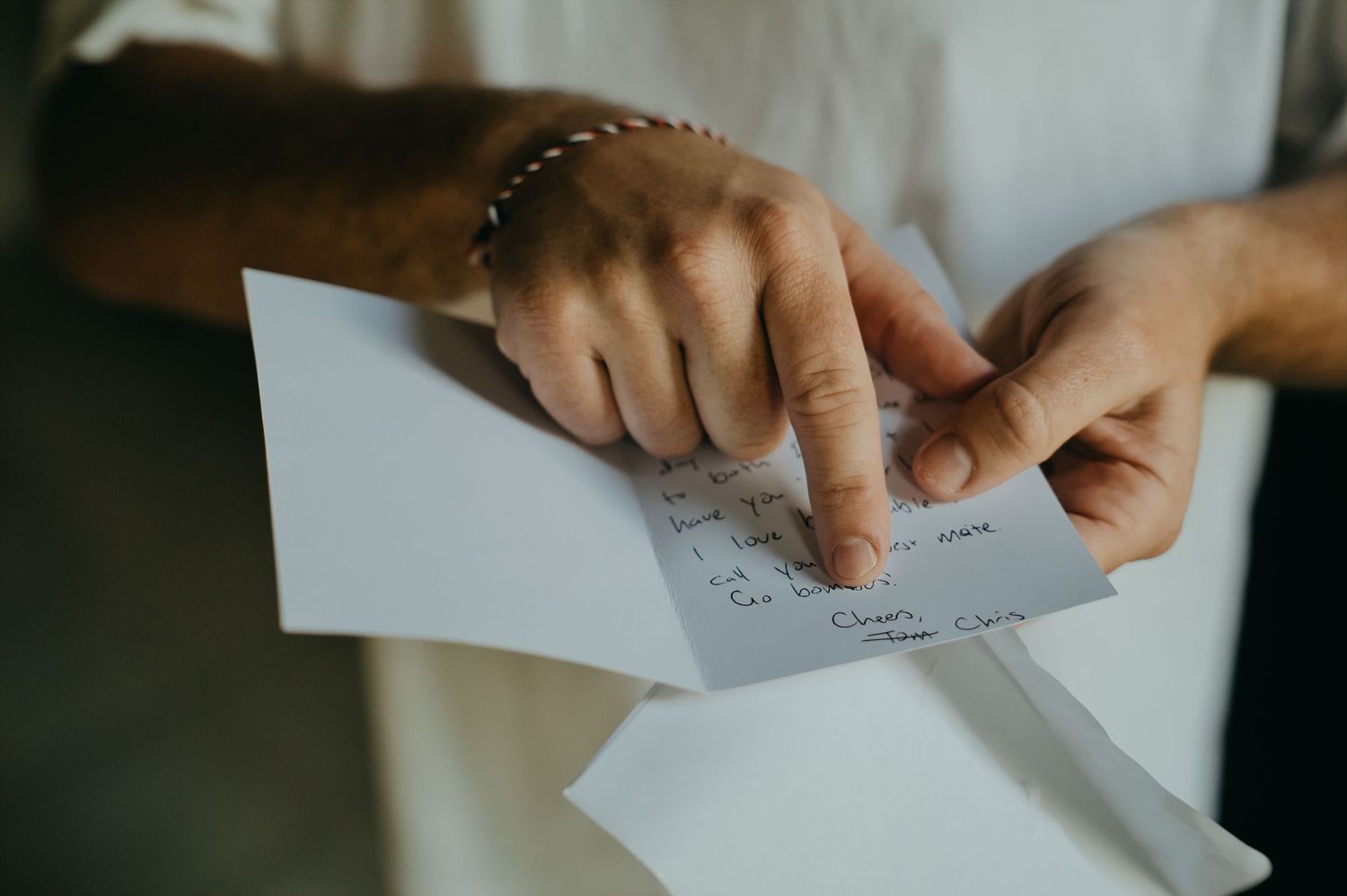 Person opening an envelope and reading a handwritten note card with cursive writing on it.