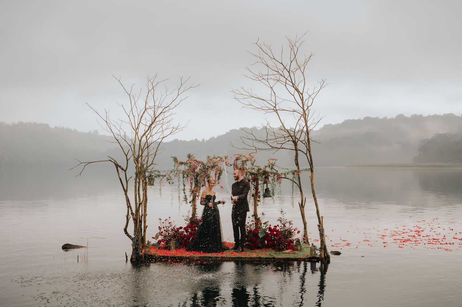 A dramatic lakeside wedding platform surrounded by dead trees in foggy conditions.