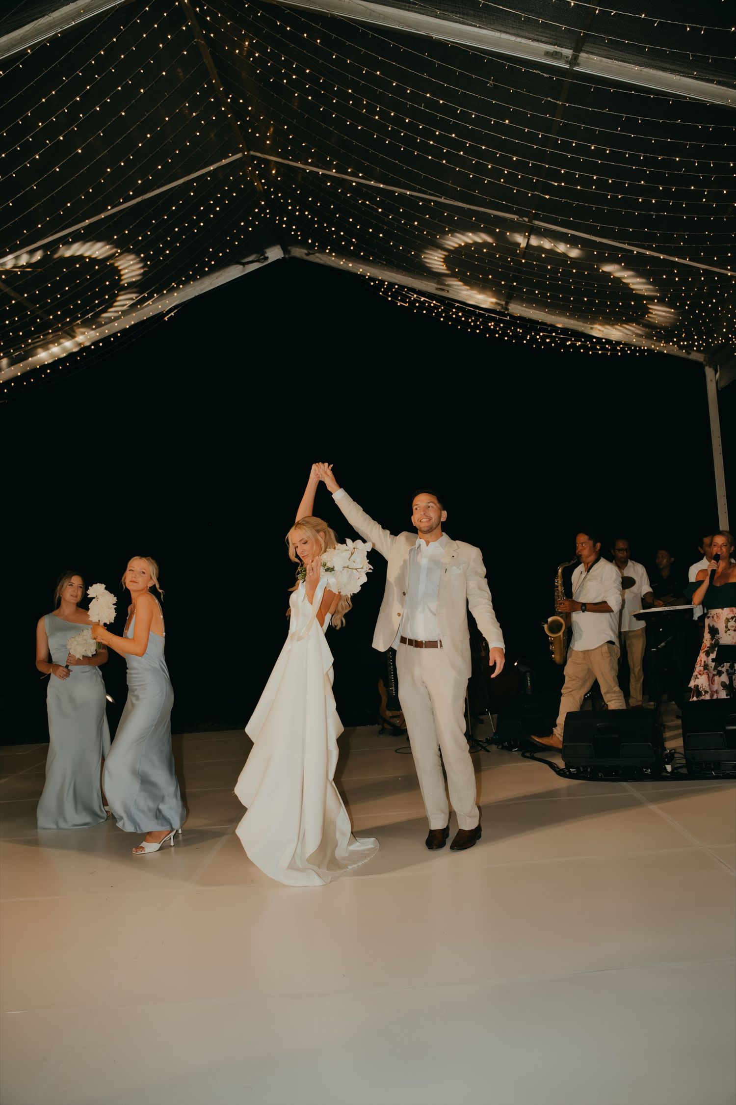 Bride and groom share their first dance under a canopy of fairy lights at their elegant wedding reception.