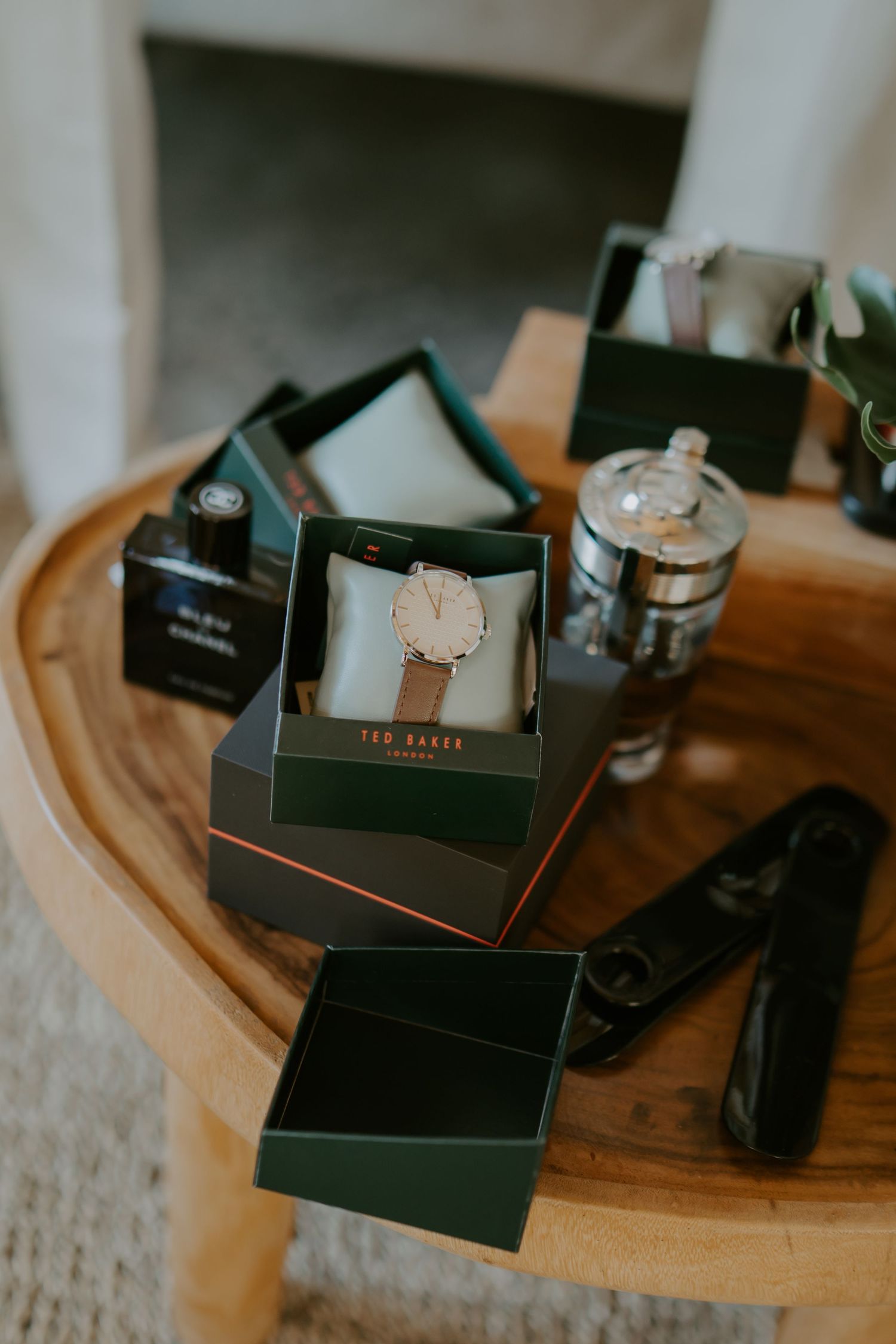 Ted Baker watch and groomsmen gift boxes arranged on a rustic wooden table before the wedding ceremony.