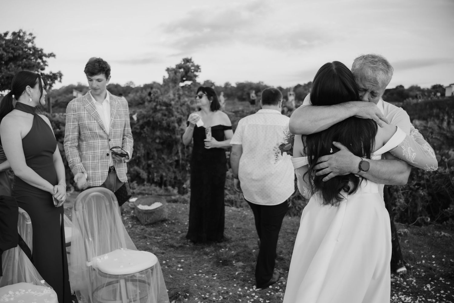 Wedding guests embrace and celebrate in a black and white outdoor ceremony photo.