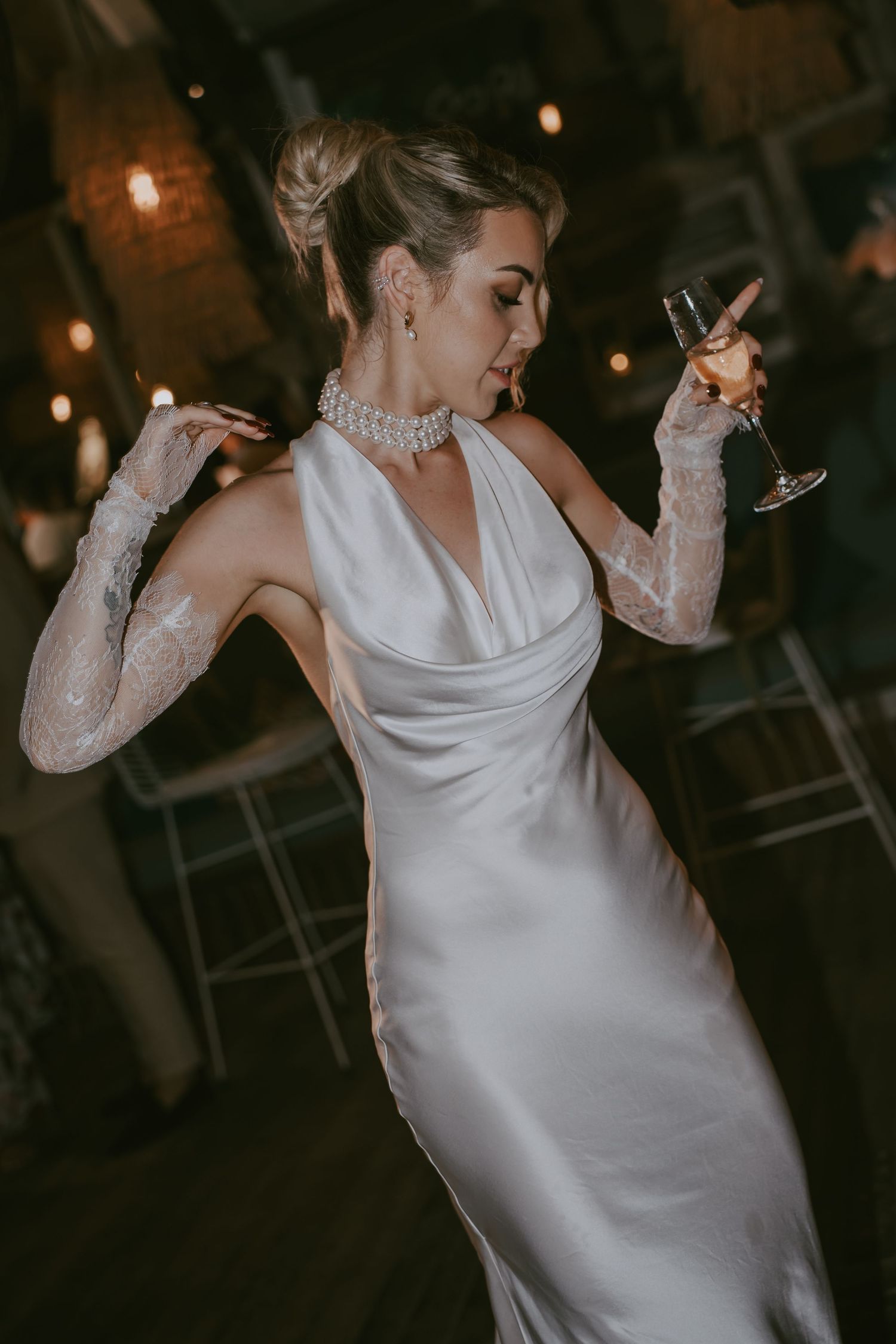 Wedding celebration with dancing and wine glasses in dimly lit venue.