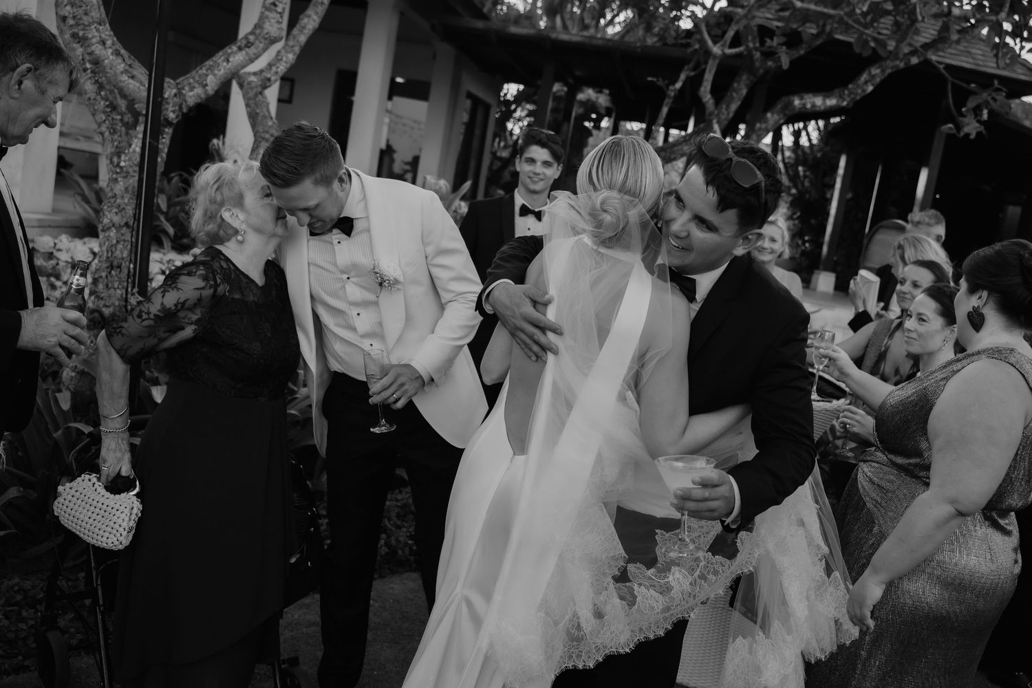 Black and white photo of wedding guests celebrating during an outdoor garden reception.