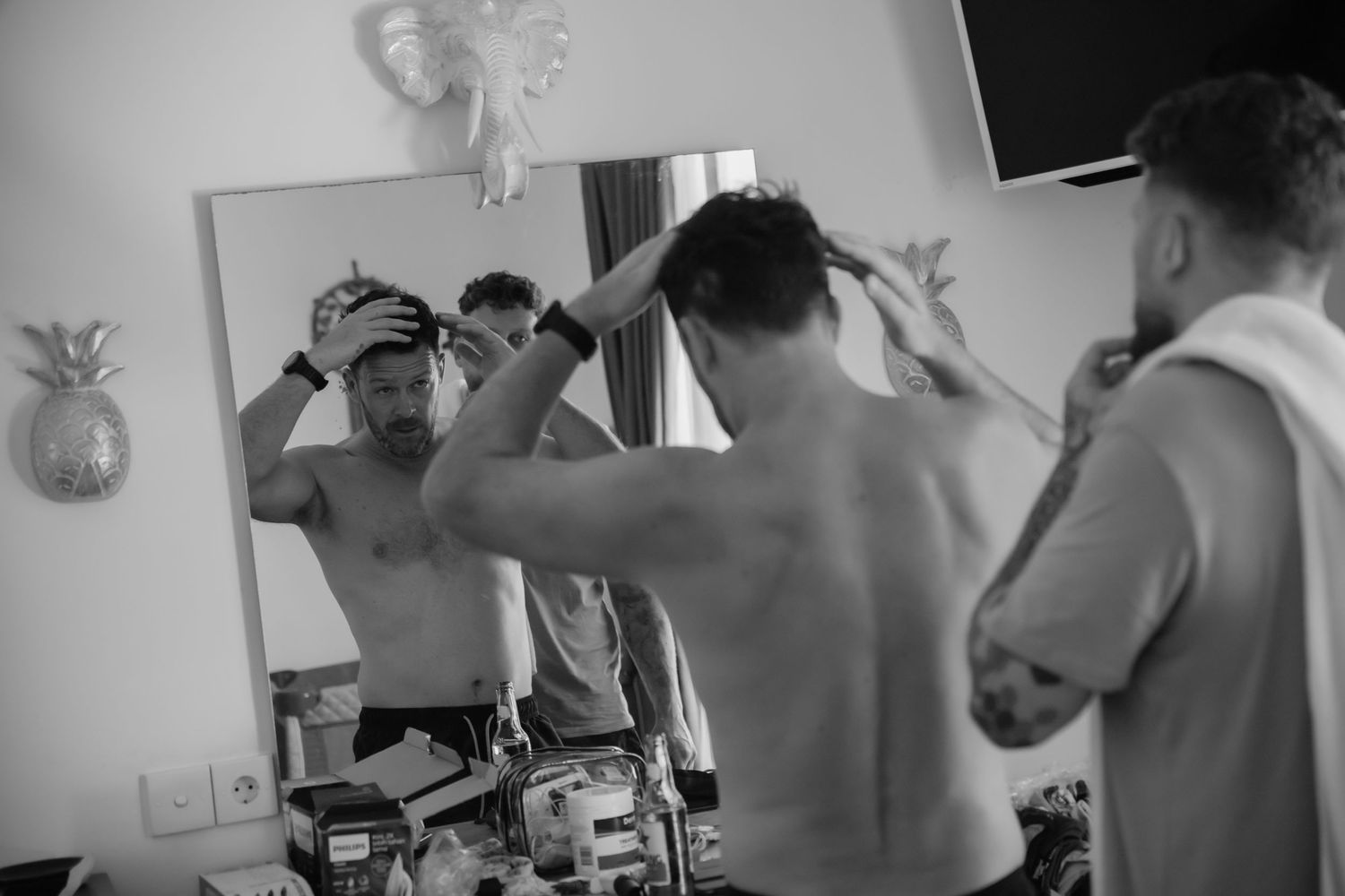 A series of black and white photos showing a person getting a haircut in a barbershop setting.
