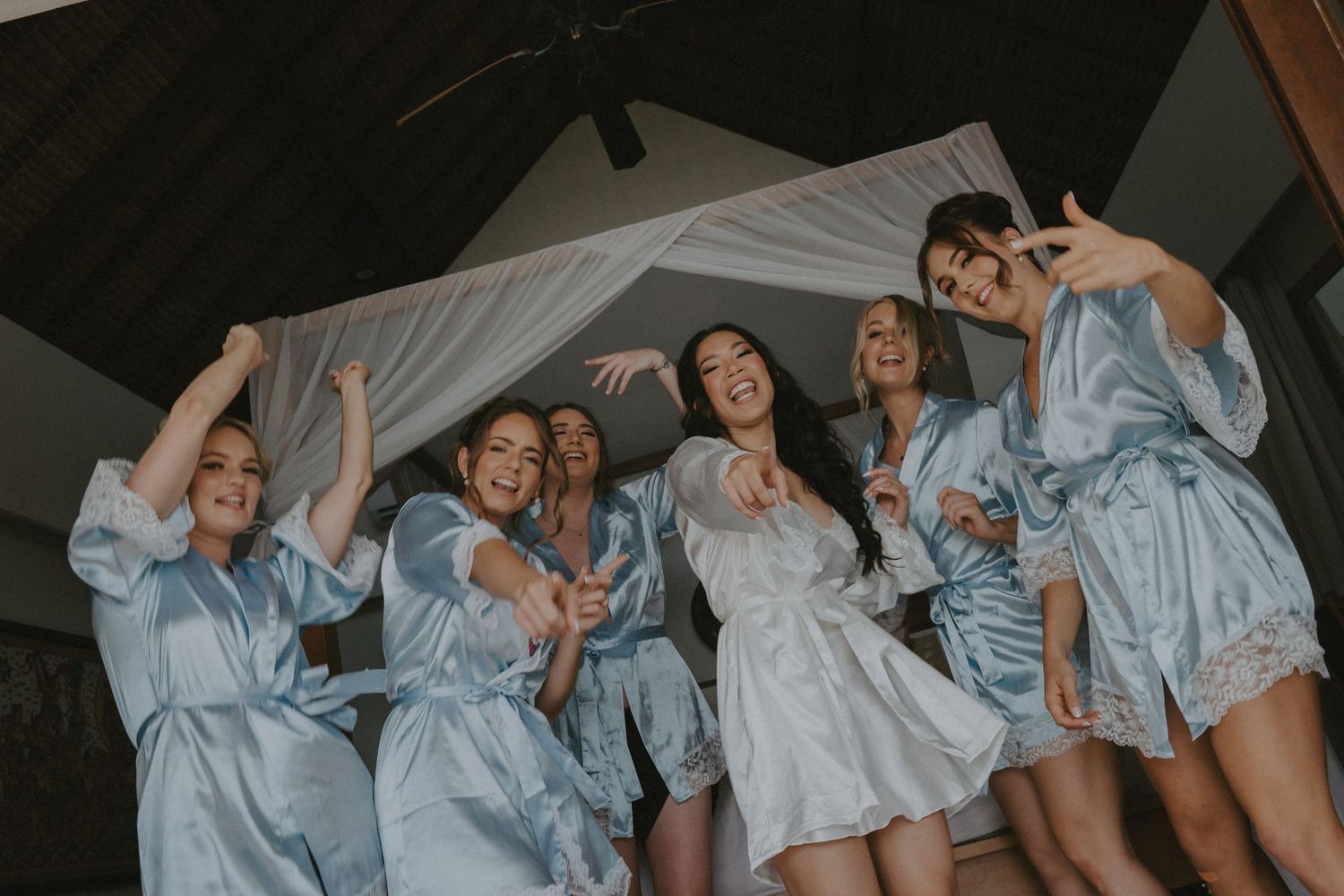 A group of people wearing matching blue outfits dance and pose together in a dimly lit room.