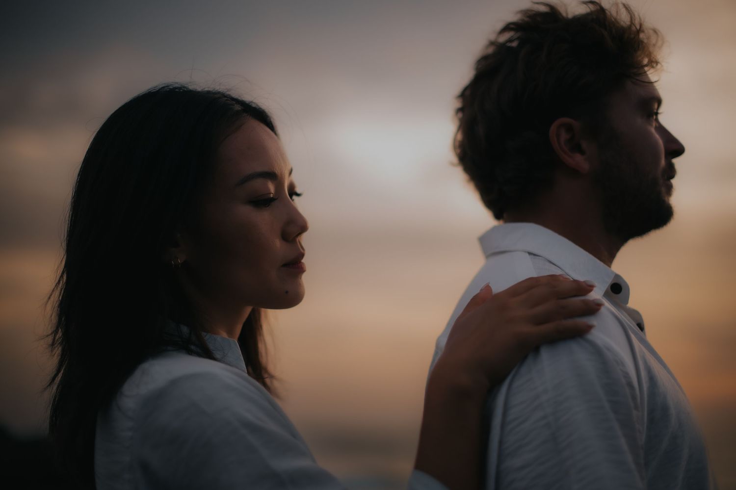 A couple embraces in silhouette against a warm sunset sky creating a romantic atmosphere.